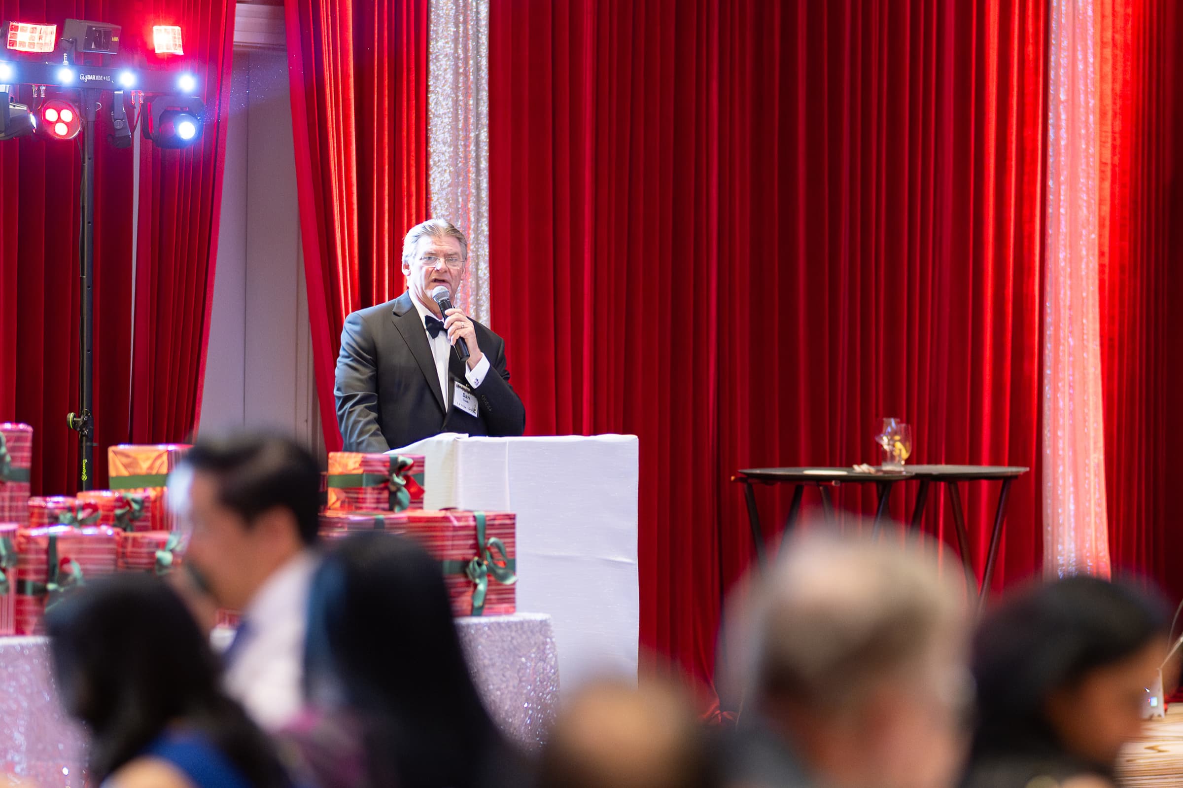 Host giving remarks with a microphone during a dinner