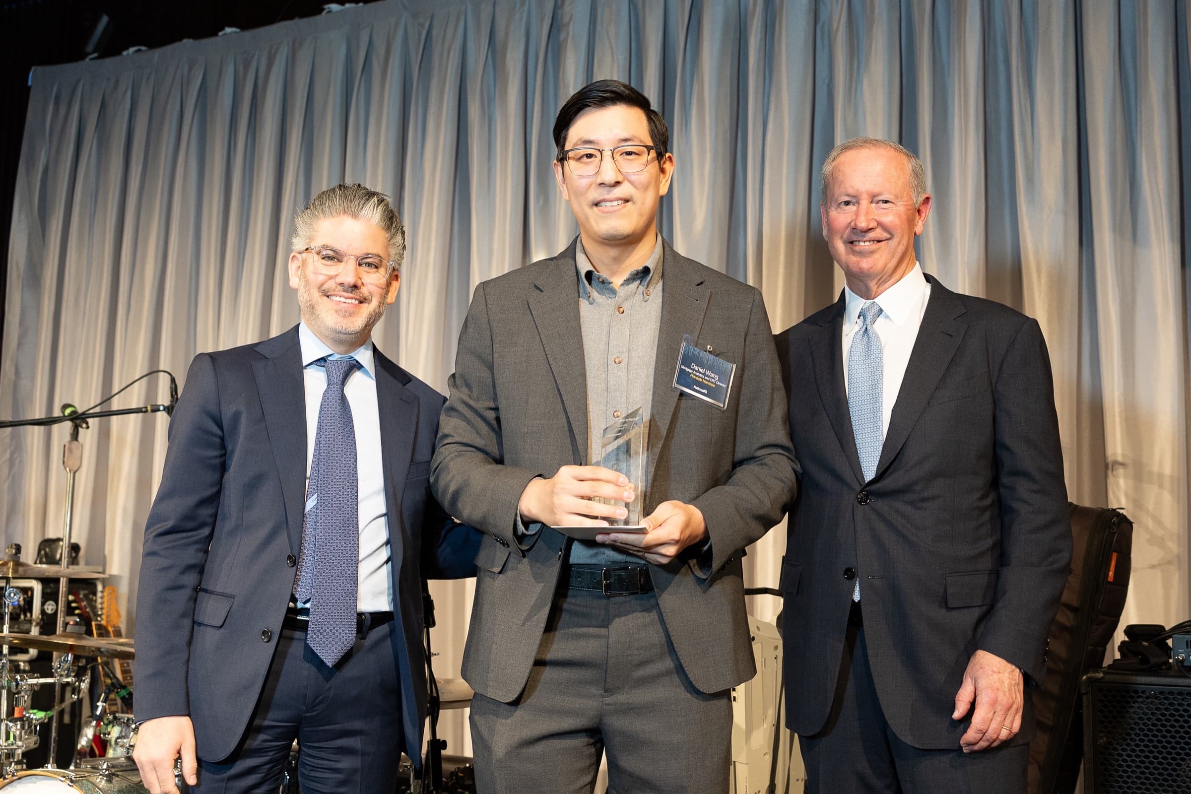 Award recipient on stage with presenters during an awards presentation