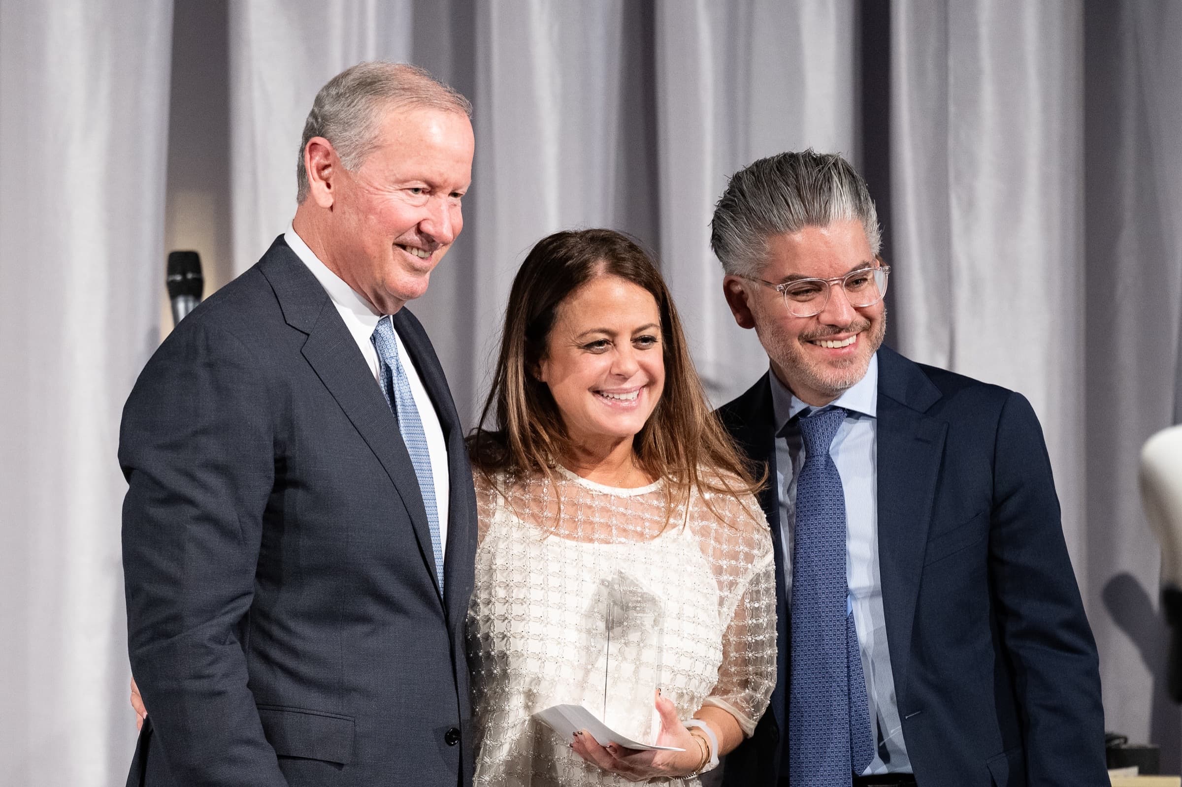 Award recipients holding their awards on stage with a presenter