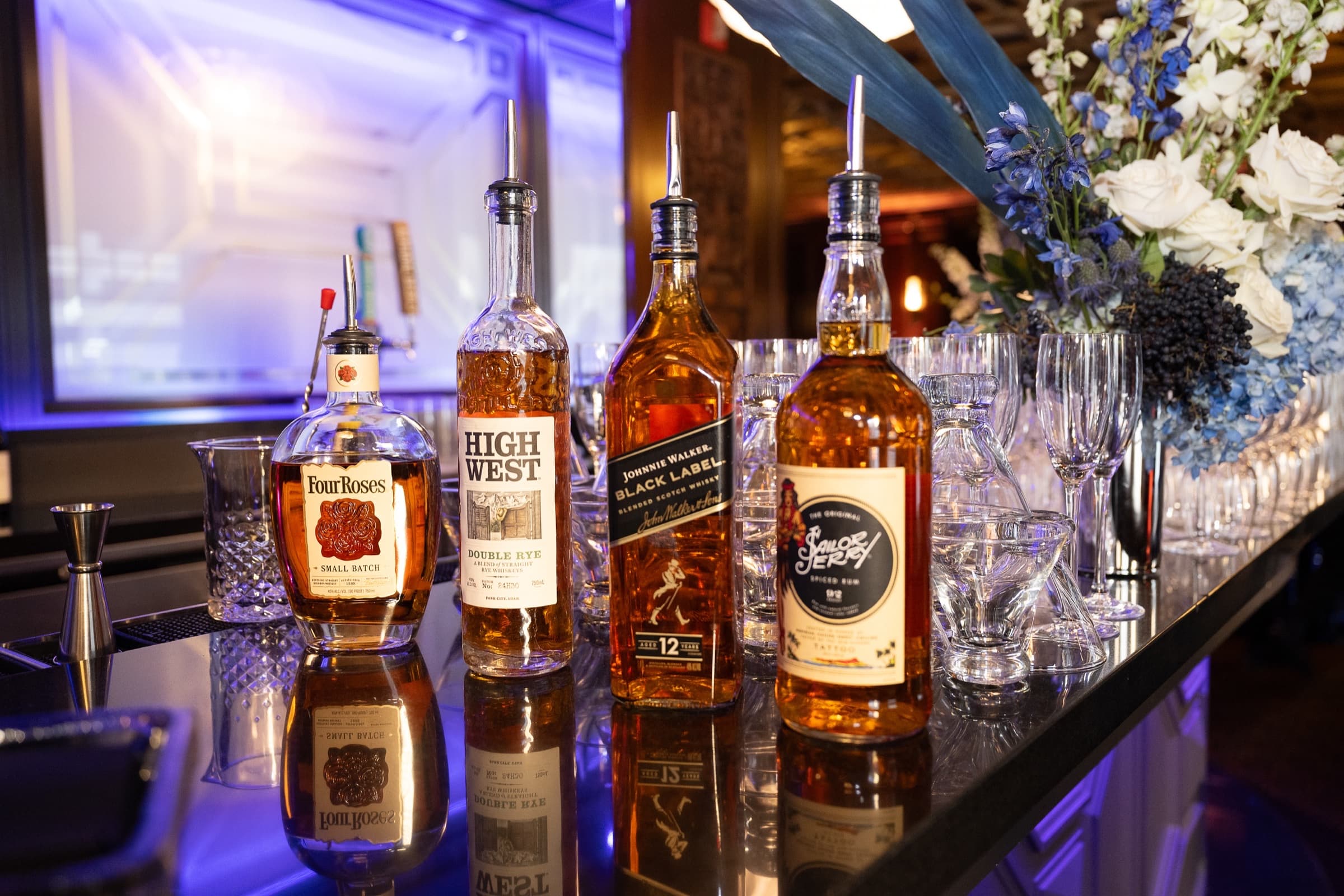 Bar detail with spirits and florals under blue uplighting at an awards evening