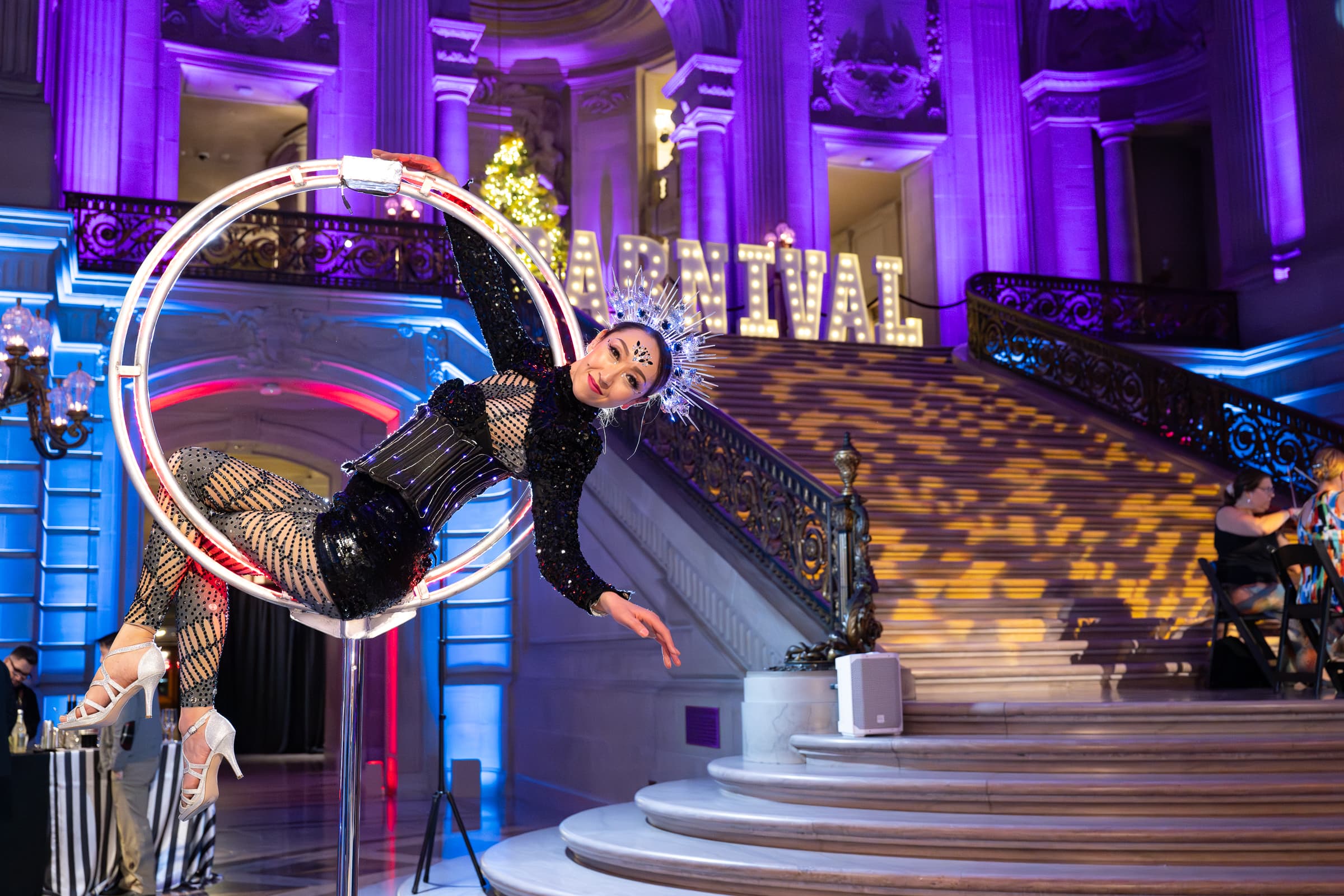 Aerial performer in a suspended hoop above a holiday party floor