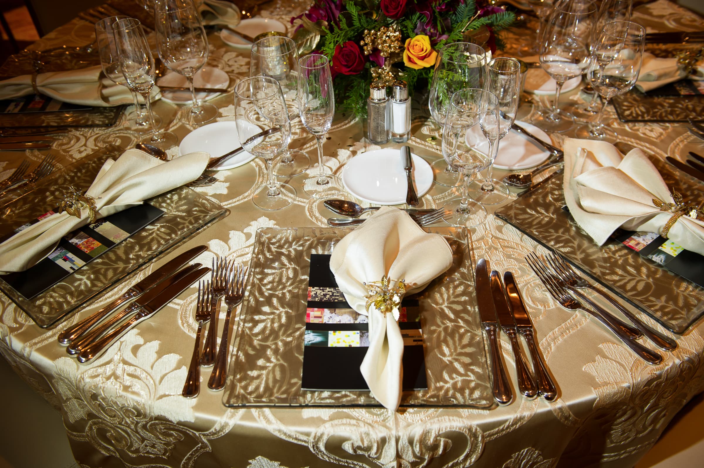 Holiday party table setting with florals, place settings, and glassware