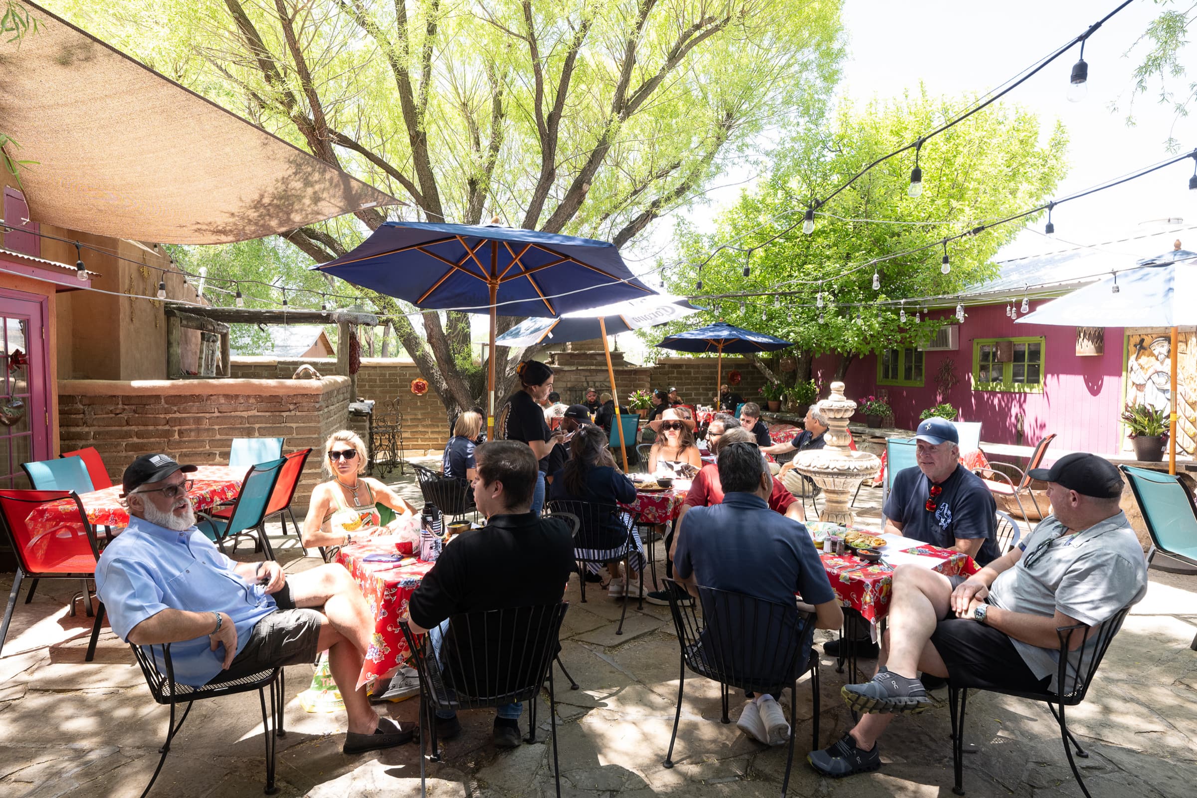 Colleagues at a shaded courtyard lunch under string lights on an offsite day