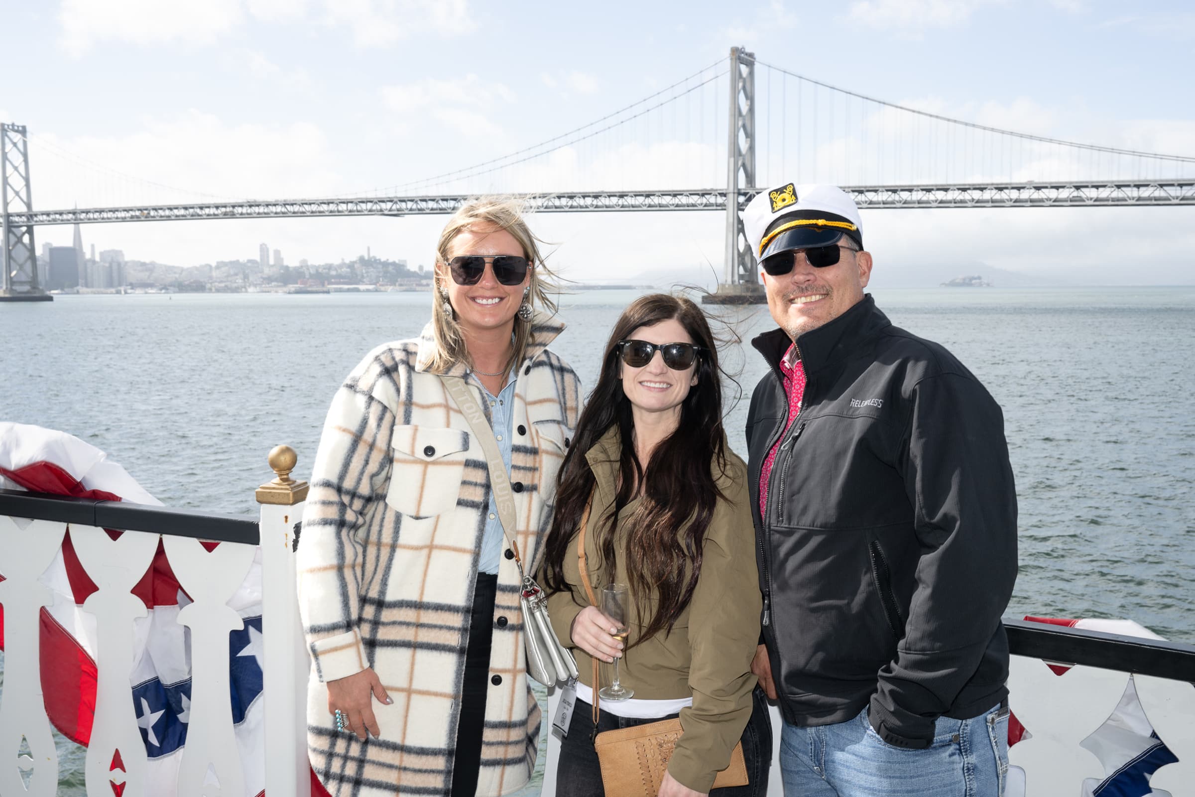 Guests on deck with a bridge and bay behind them