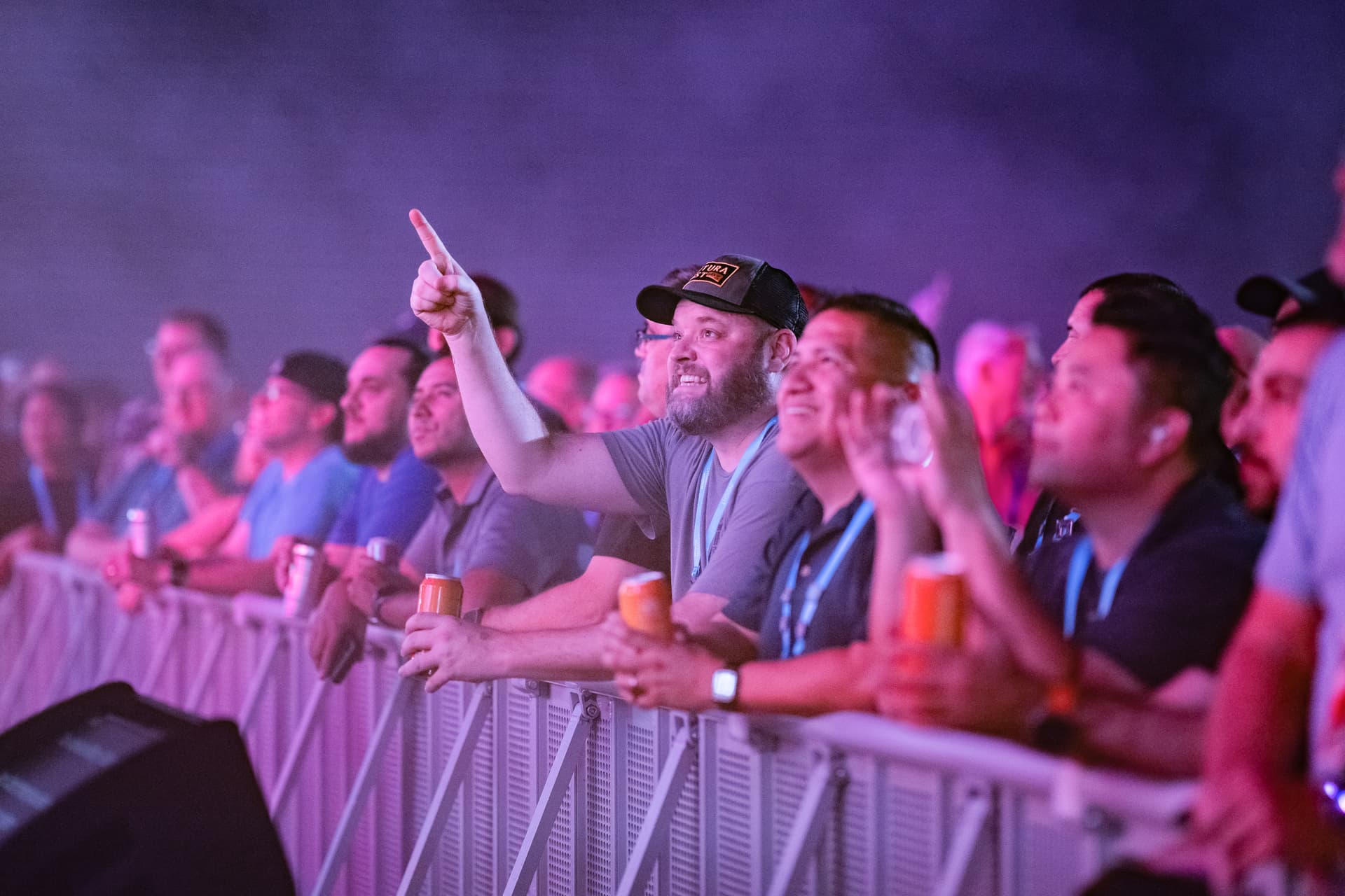 Group of engaged attendees cheering with drinks at neon-lit evening event