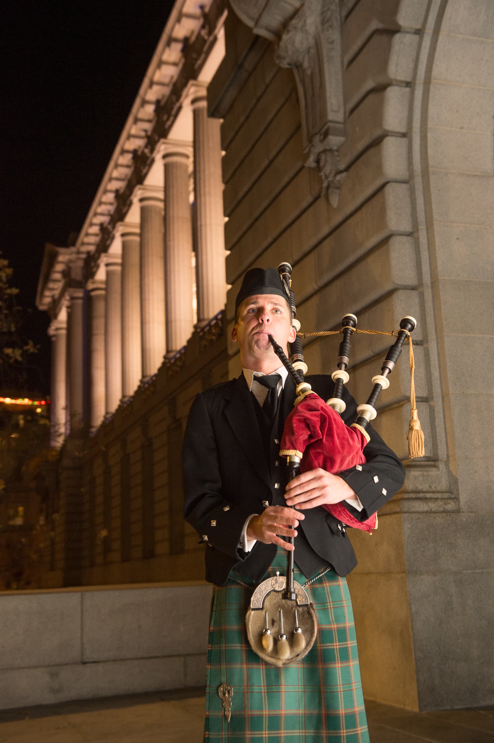 Piper performing beside a stone colonnade at an evening event