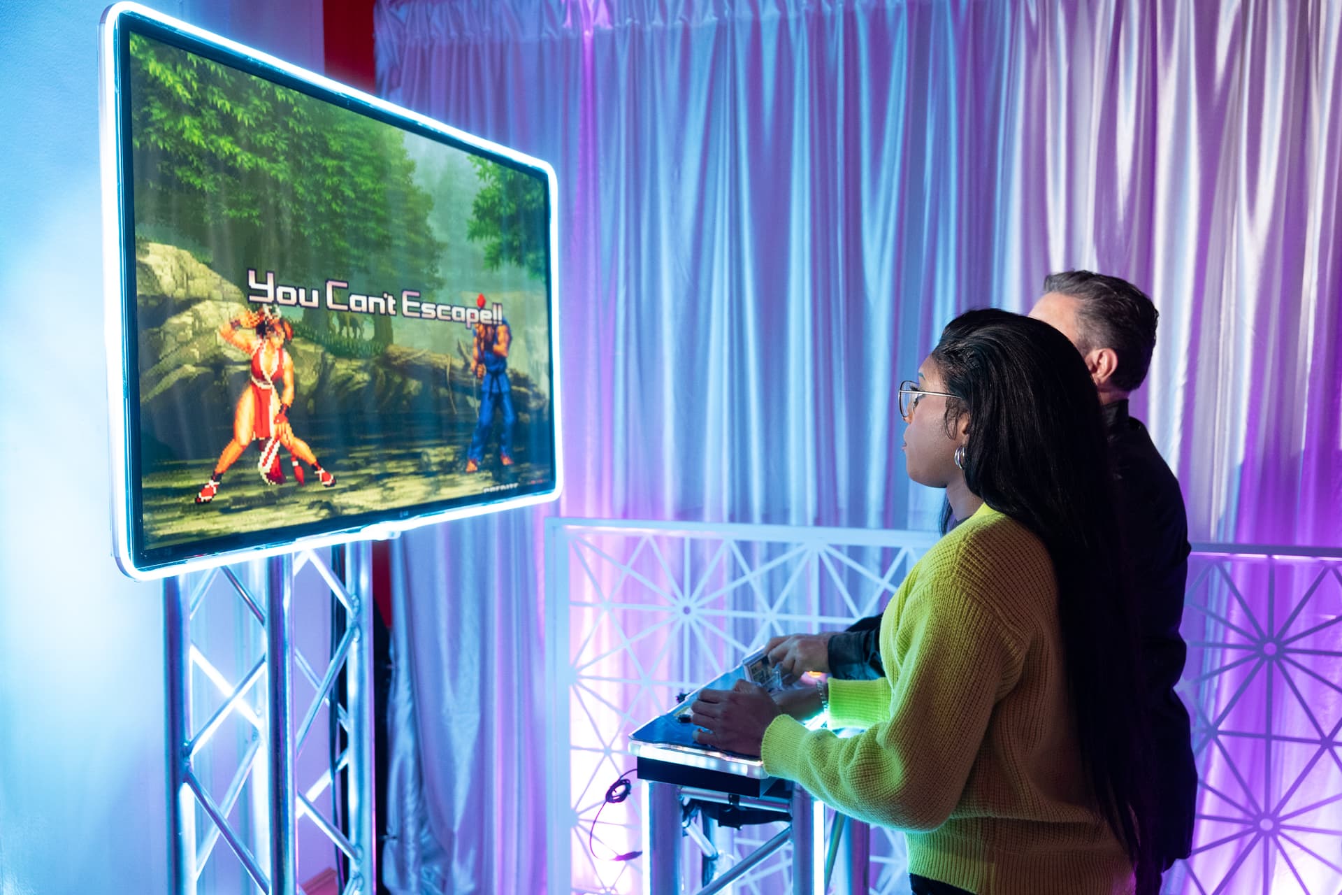 Visitors interact with a large illuminated game display featuring vibrant graphics projected onto a vertical surface