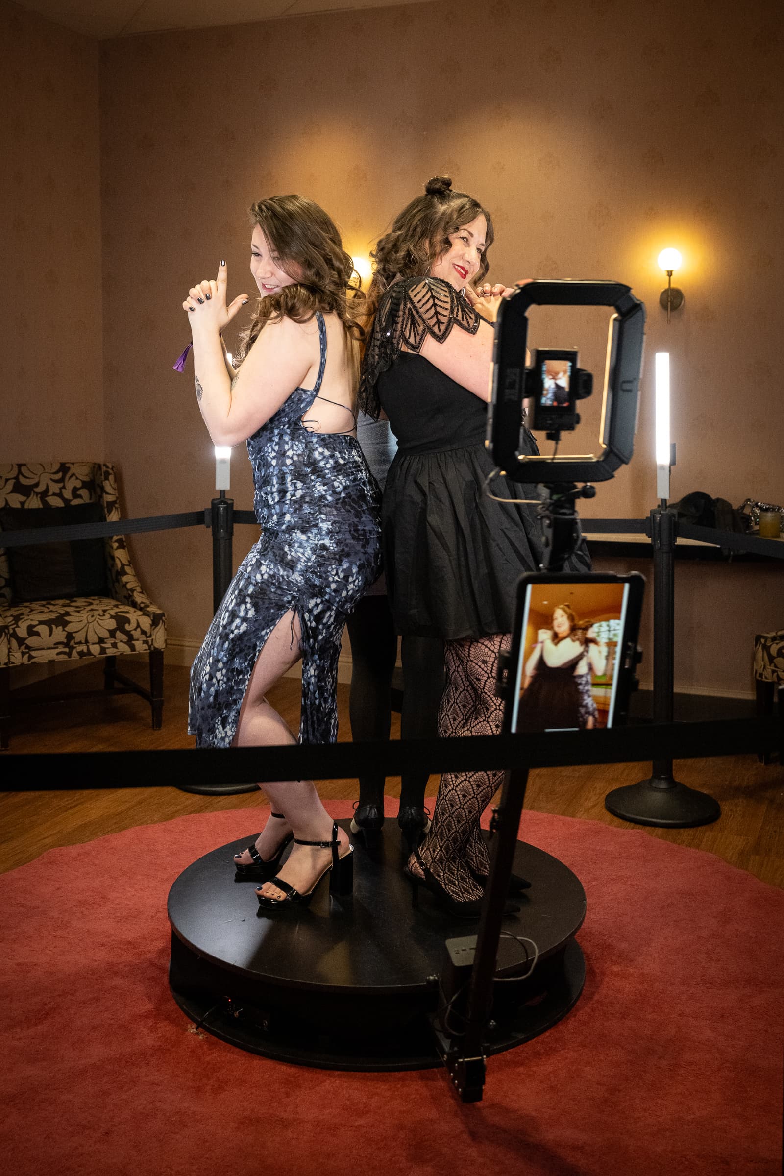 Two women pose playfully at an interactive digital mirror installation with dramatic off-camera lighting
