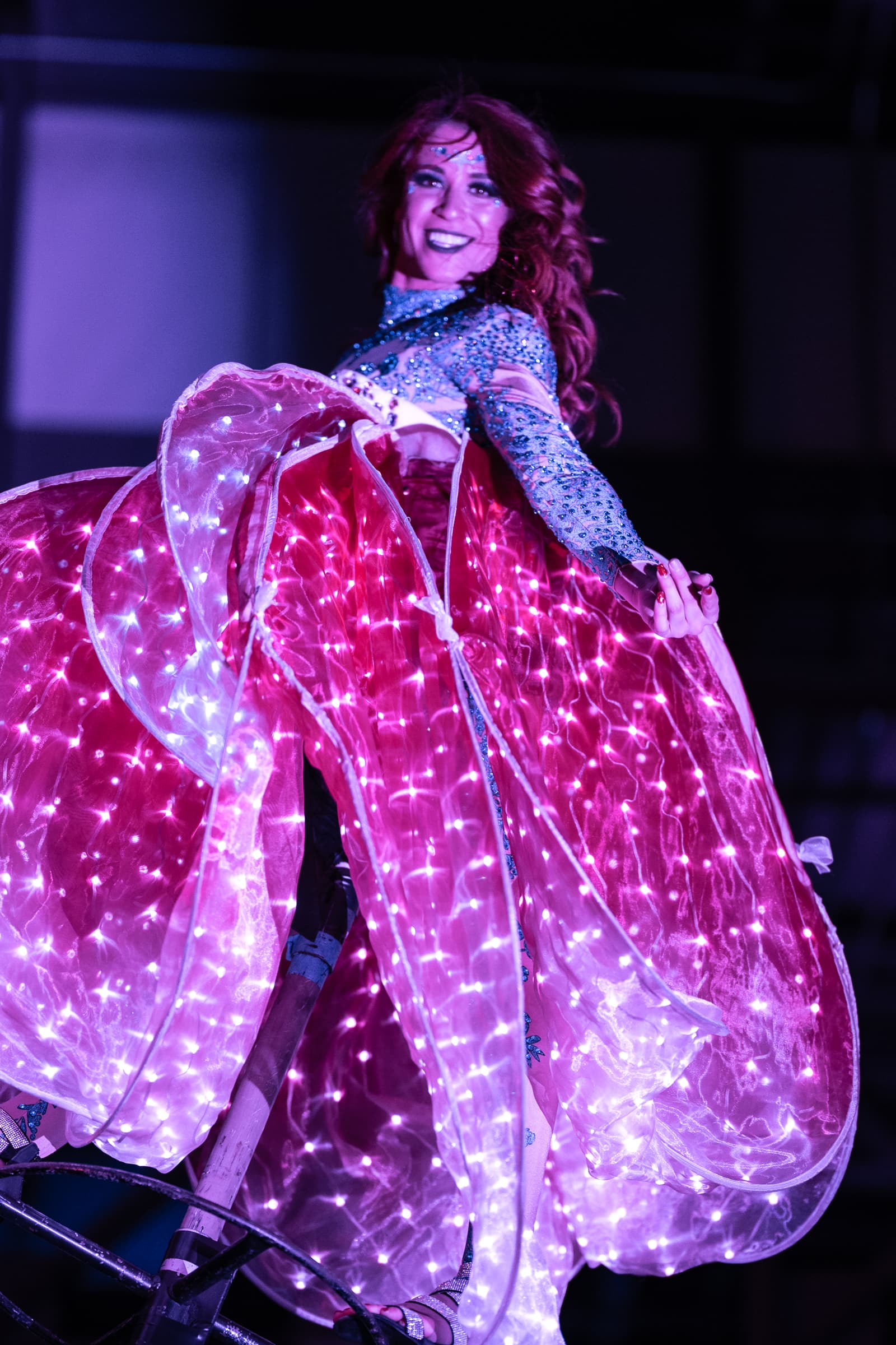 Performer in an illuminated LED gown lit magenta