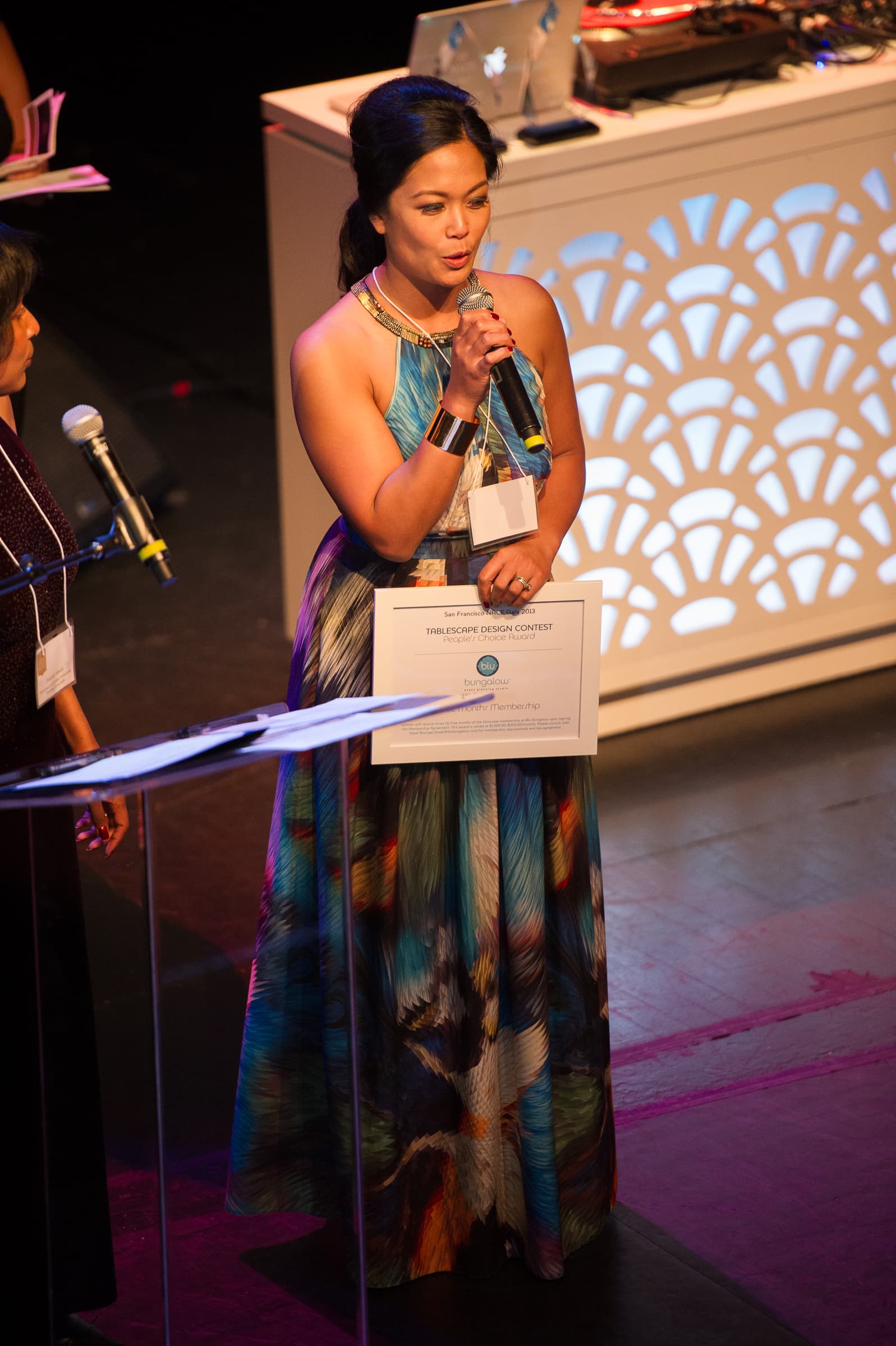 Performer singing beside a decorative screen at a gala