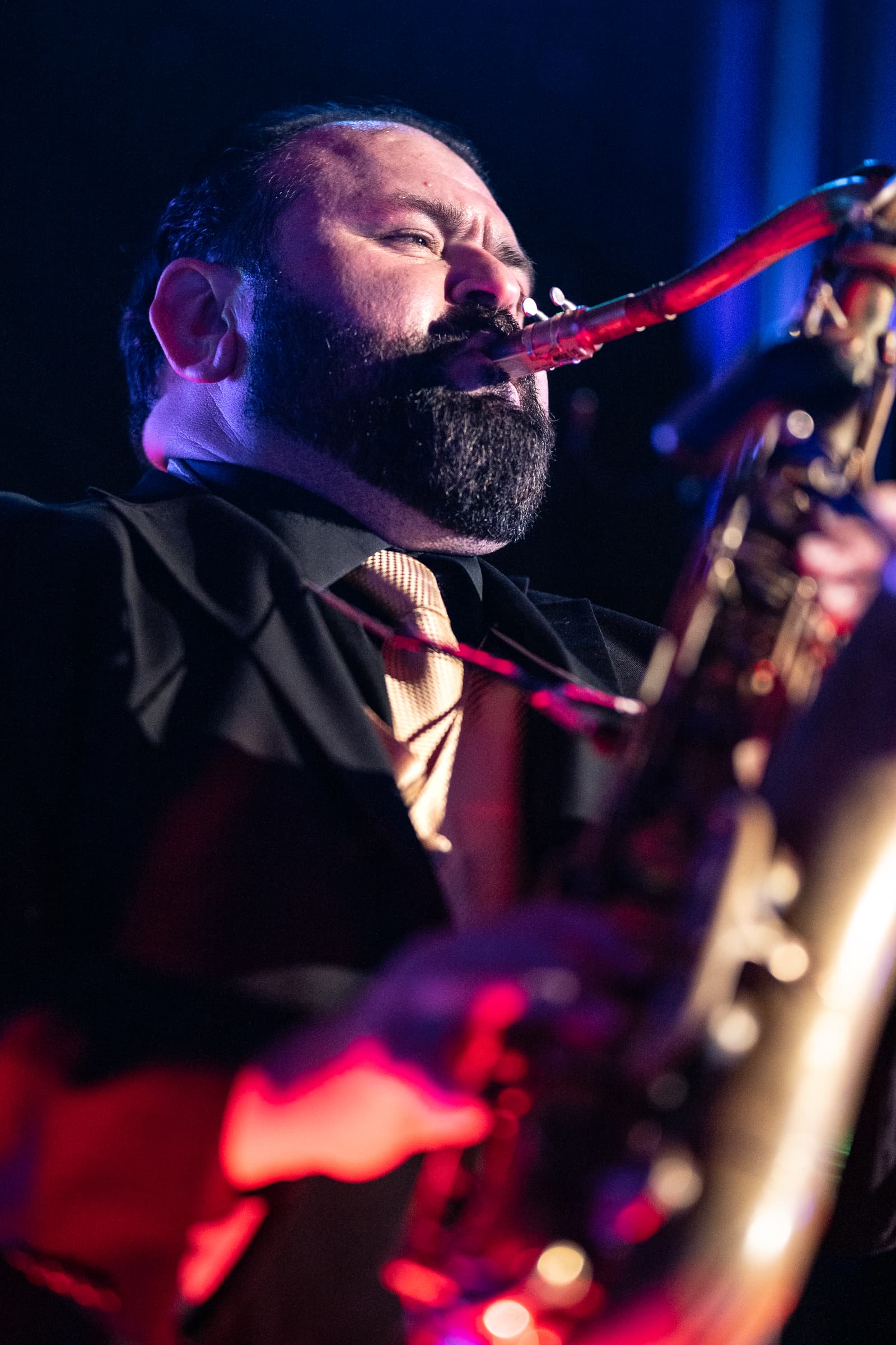 Vocalist performing into a microphone under deep red stage light