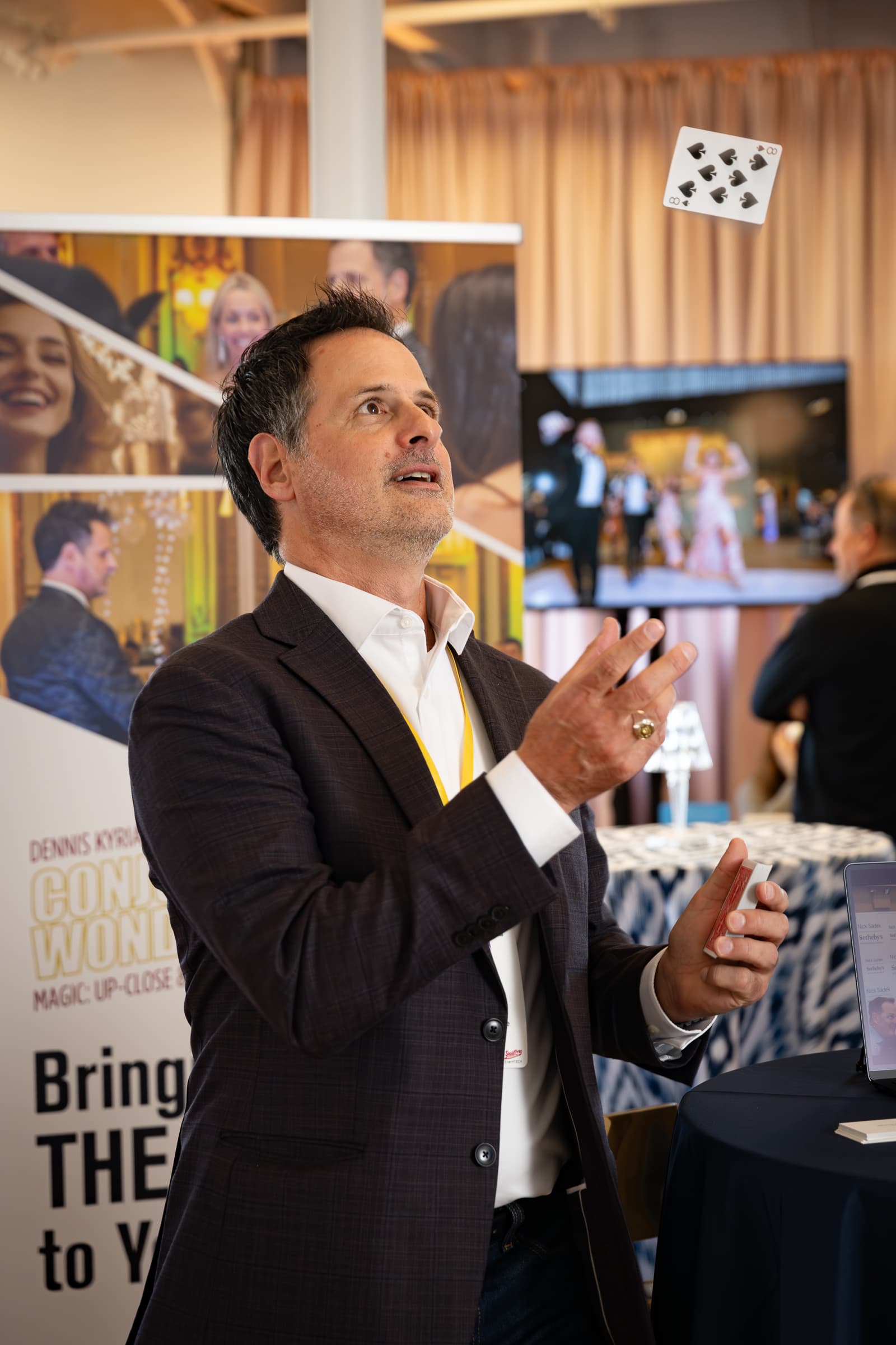 Man in business suit speaking with animated hand gestures at vendor showcase event