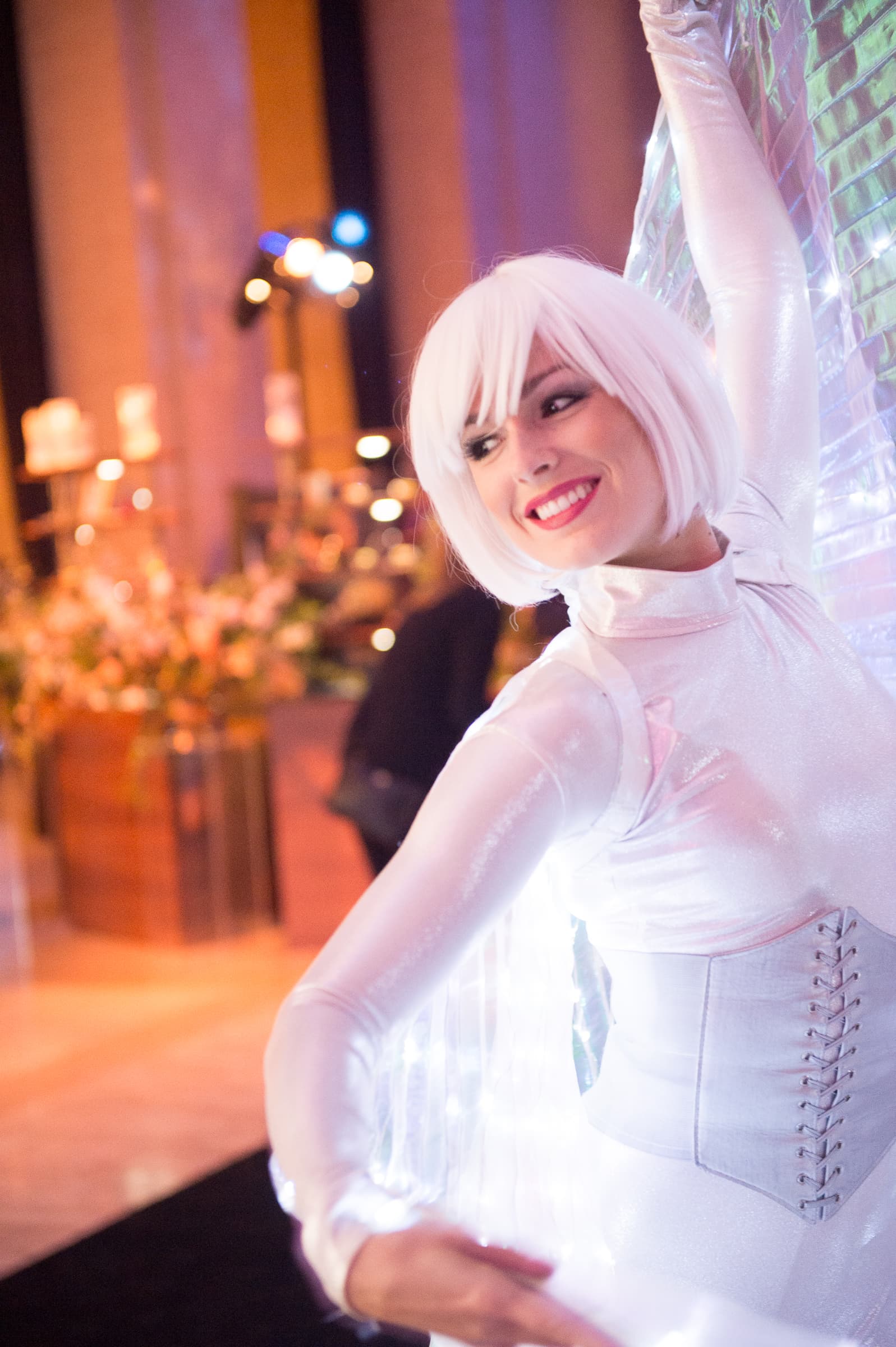 Performer in a white illuminated costume greeting guests