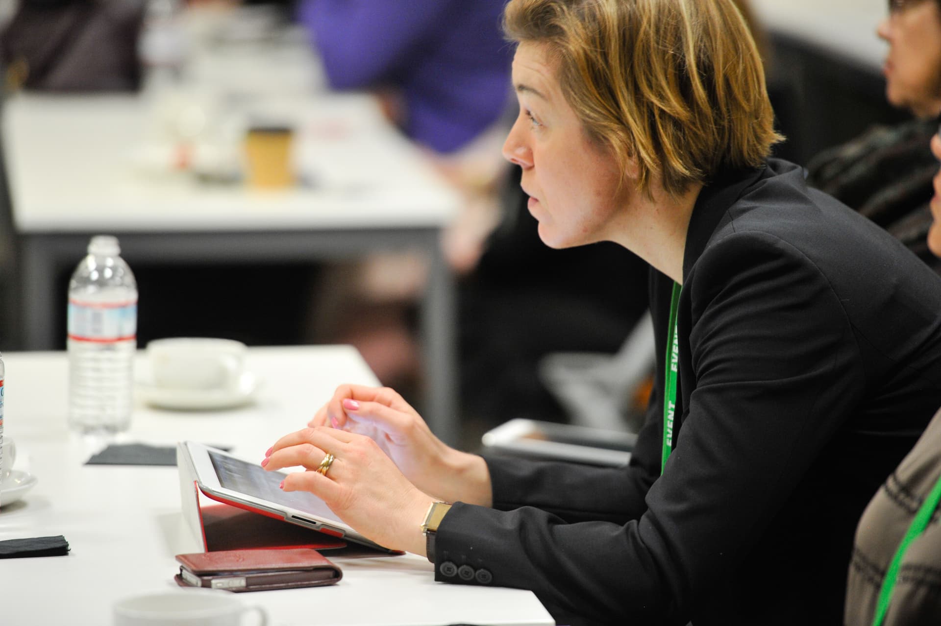 Attendee taking notes on a tablet at a working session table