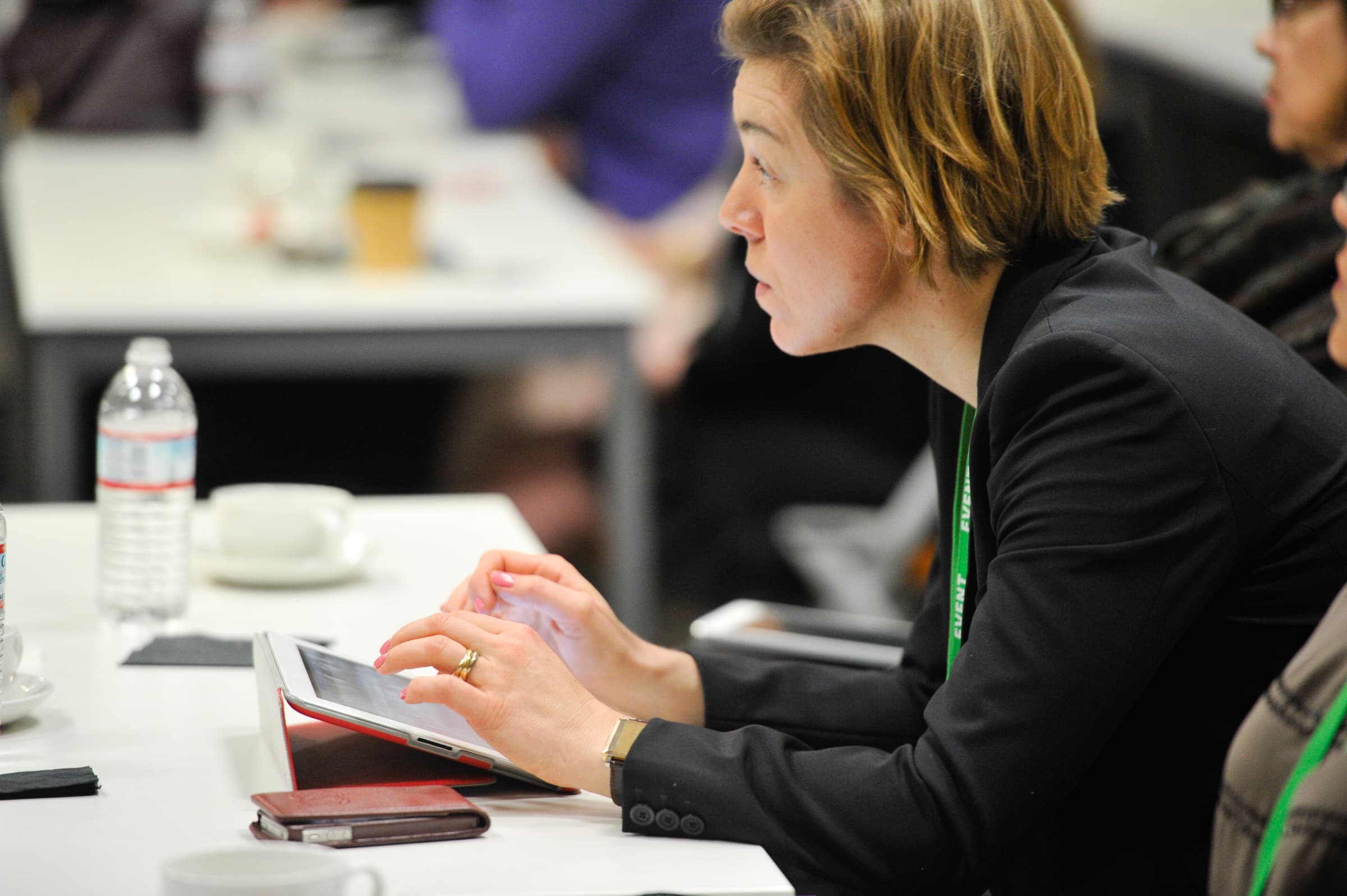 Attendee taking notes on a tablet at a working session table