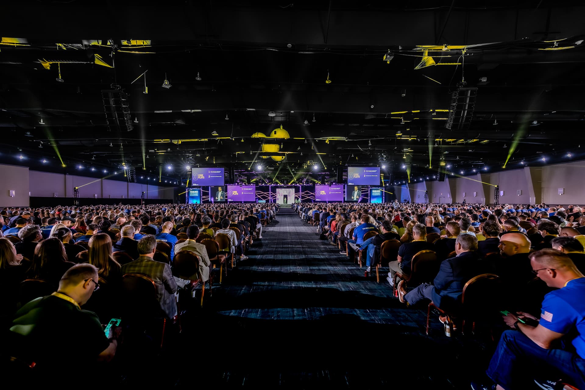 Conference attendees seated in breakout session with stage and lighting setup