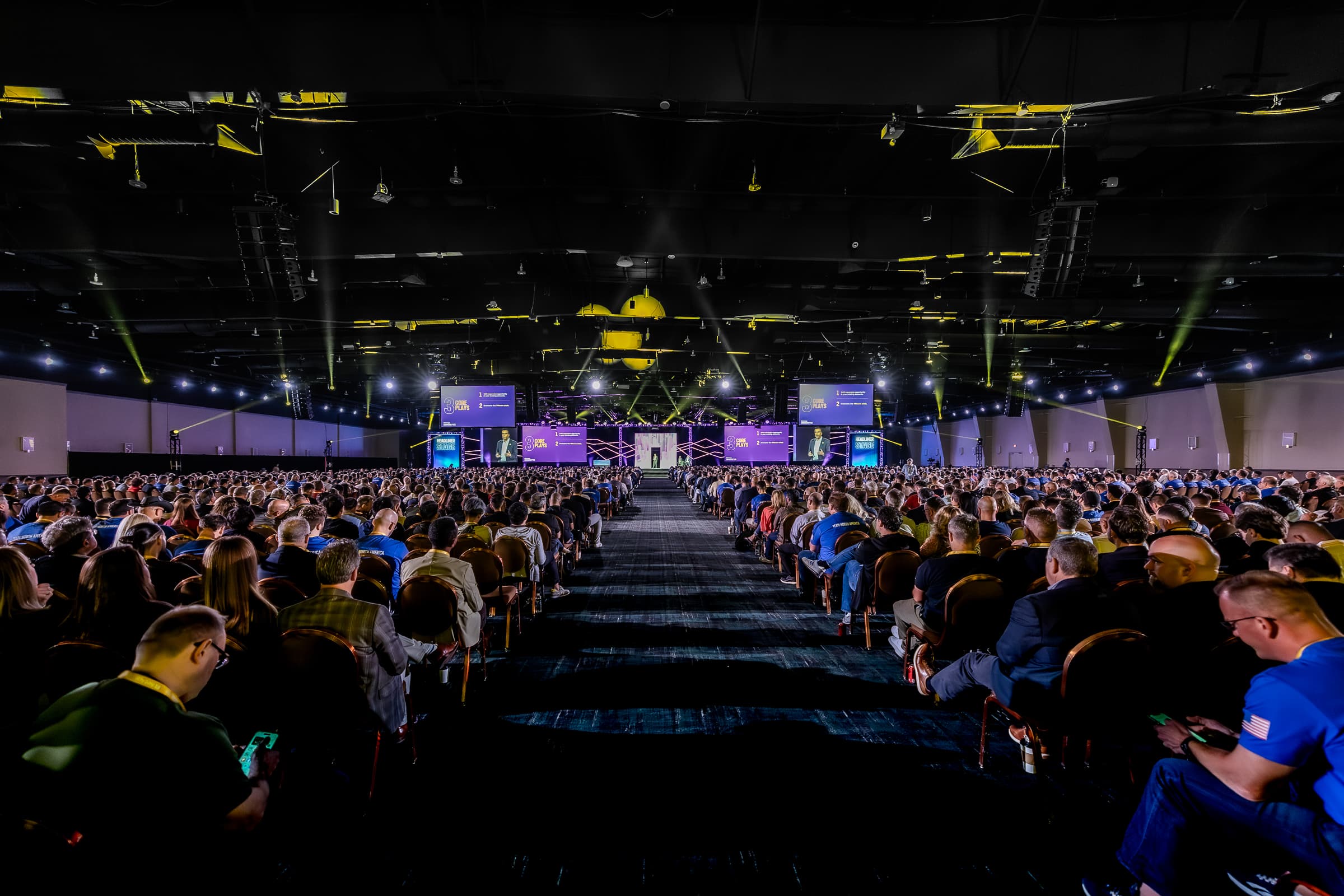 Conference attendees seated in breakout session with stage and lighting setup