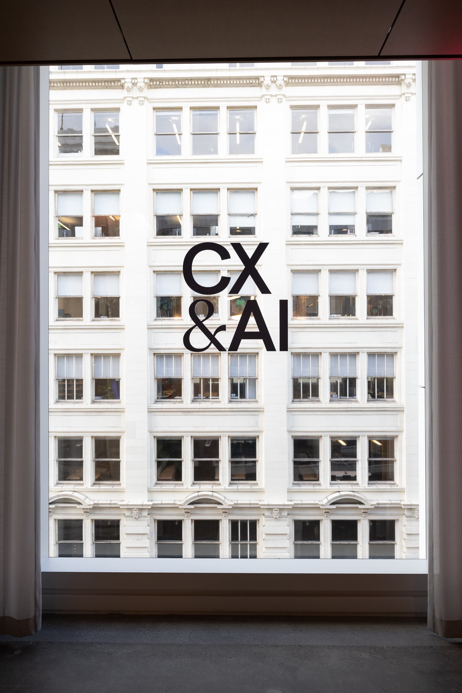 CX and AI event lettering on a Convene window overlooking a neighboring San Francisco building