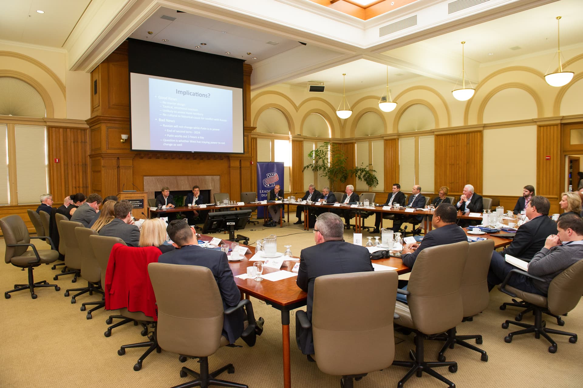 Executives seated around a hollow-square boardroom set for a working session