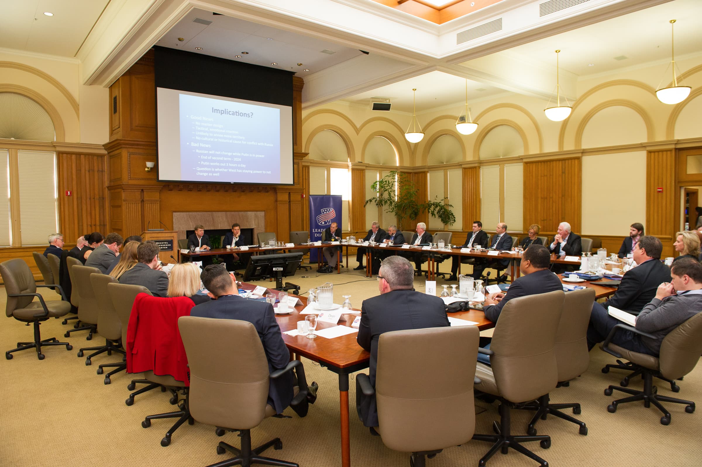 Executives seated around a hollow-square boardroom set for a working session