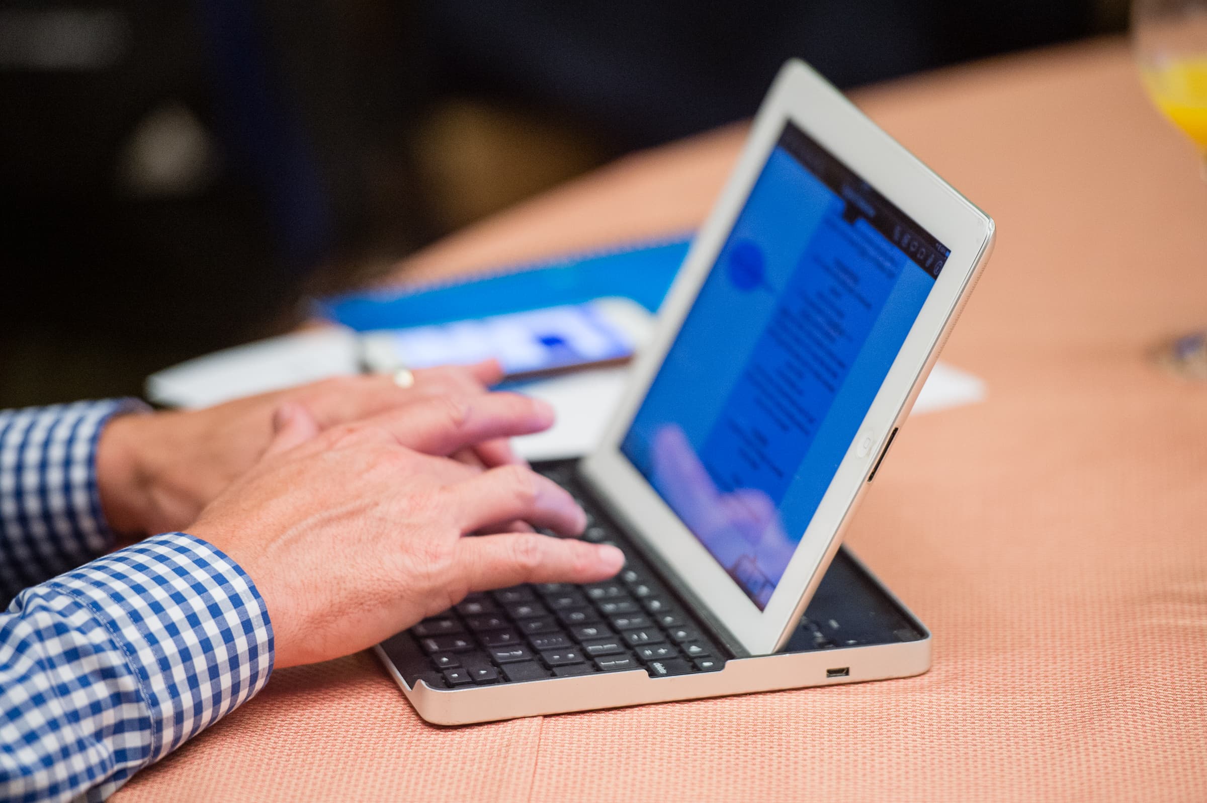 Hands typing on a laptop keyboard during a conference session