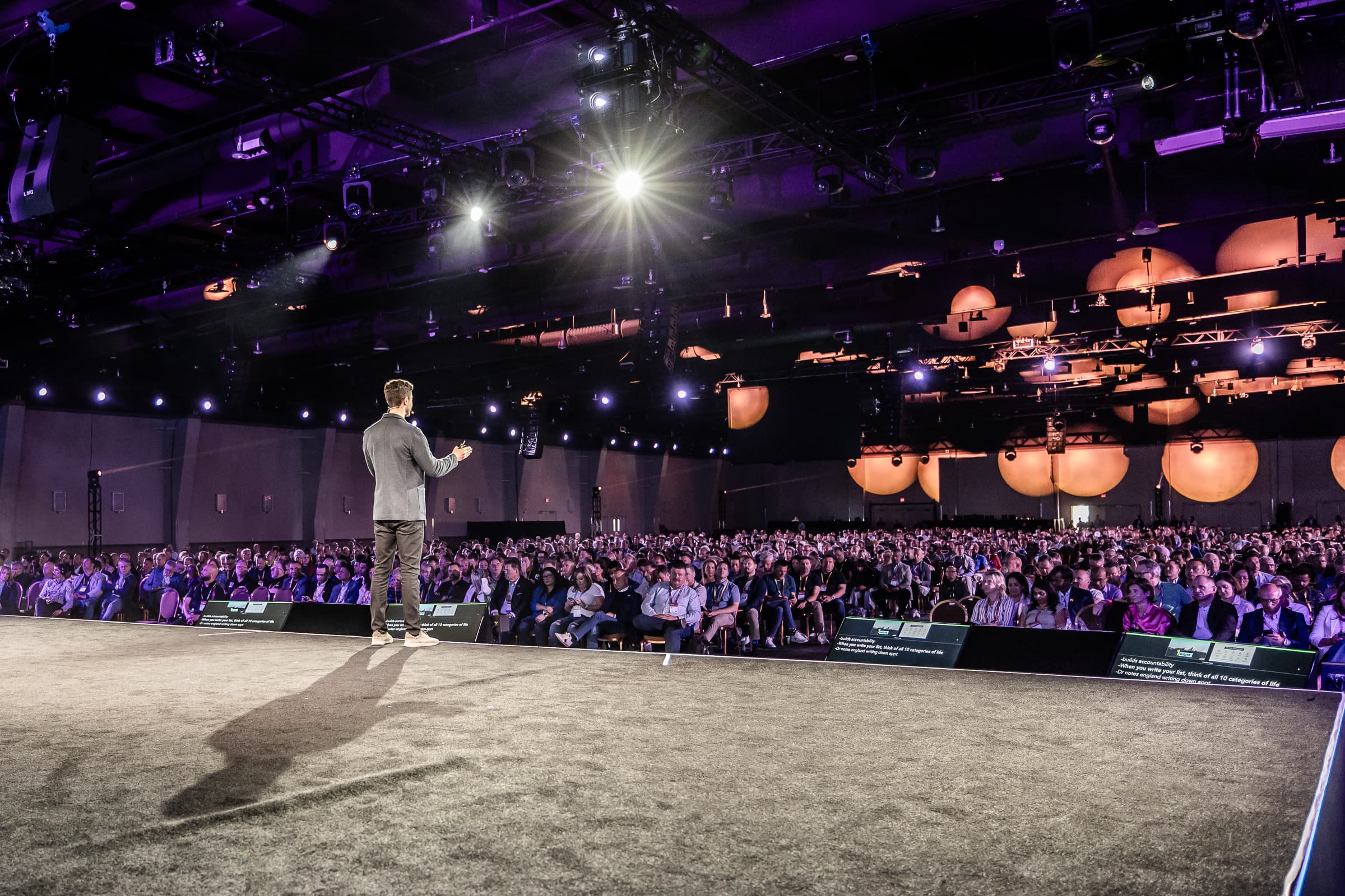 Single keynote speaker presenting to large seated audience in main conference ballroom