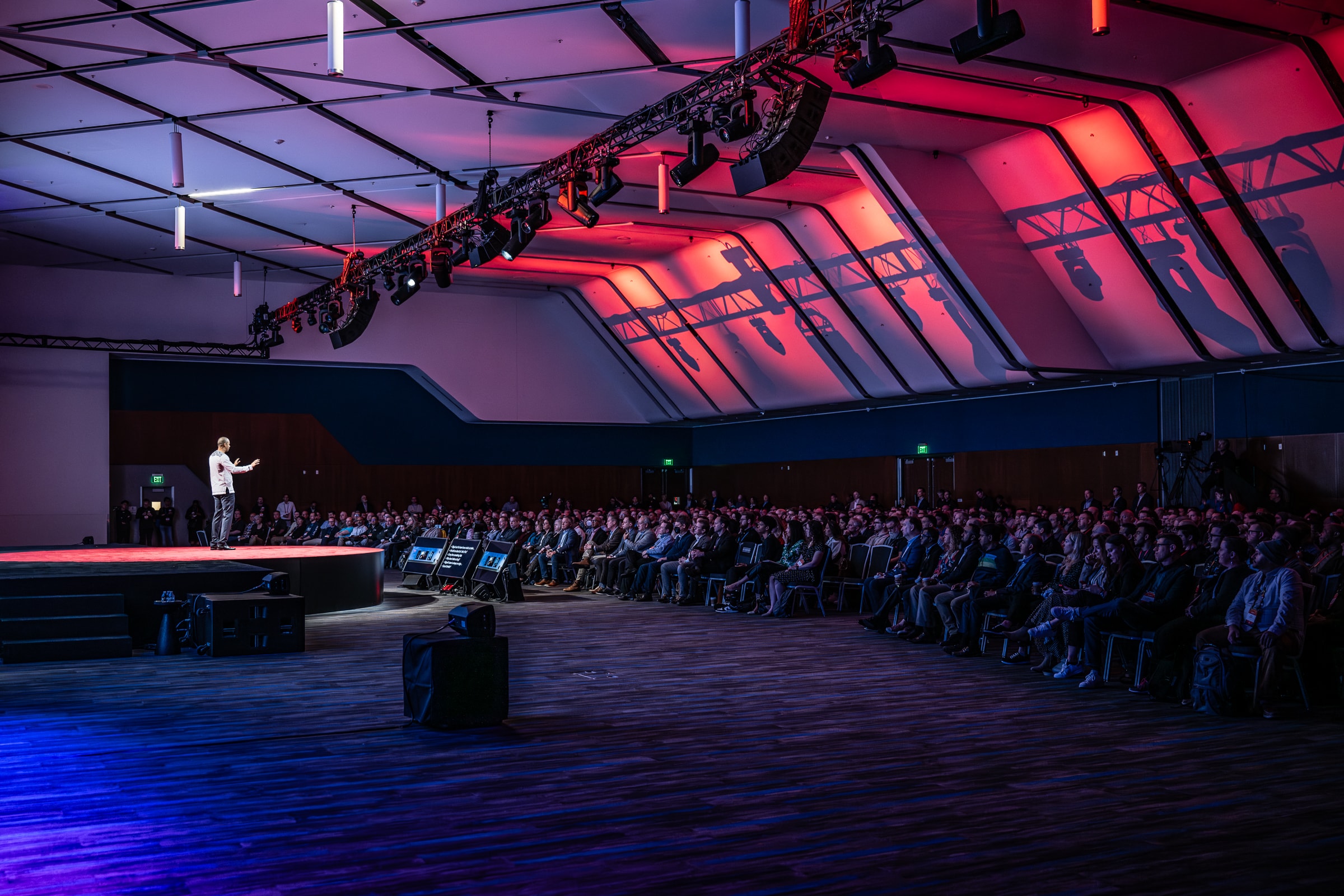 Speaker presenting on a dramatically lit conference keynote stage