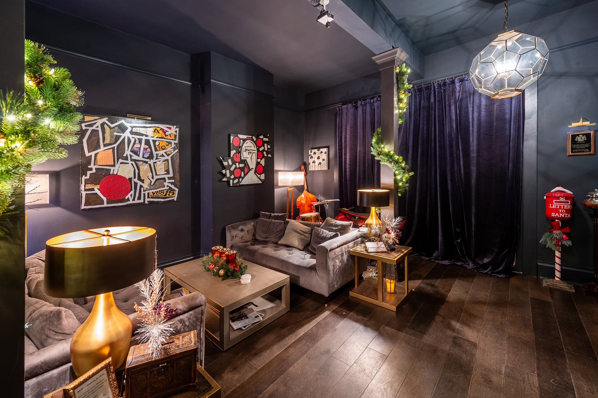 Intimate lounge at The Academy with velvet seating, framed artwork, holiday greenery, and warm table lamps