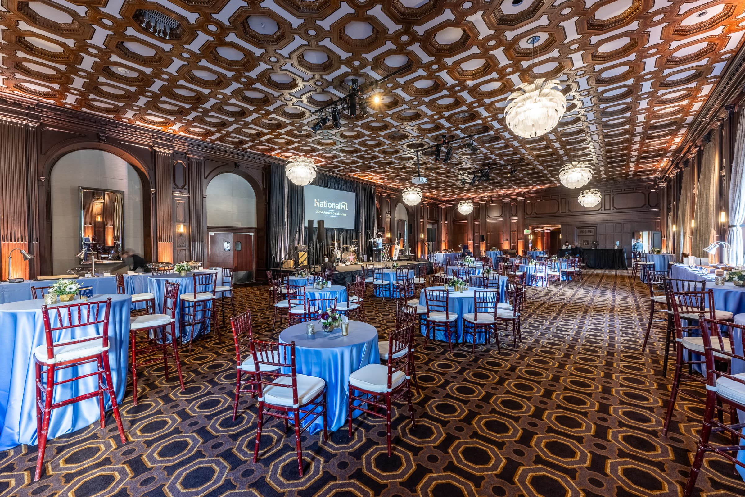 Historic ballroom set with round tables and blue linens before guests arrive