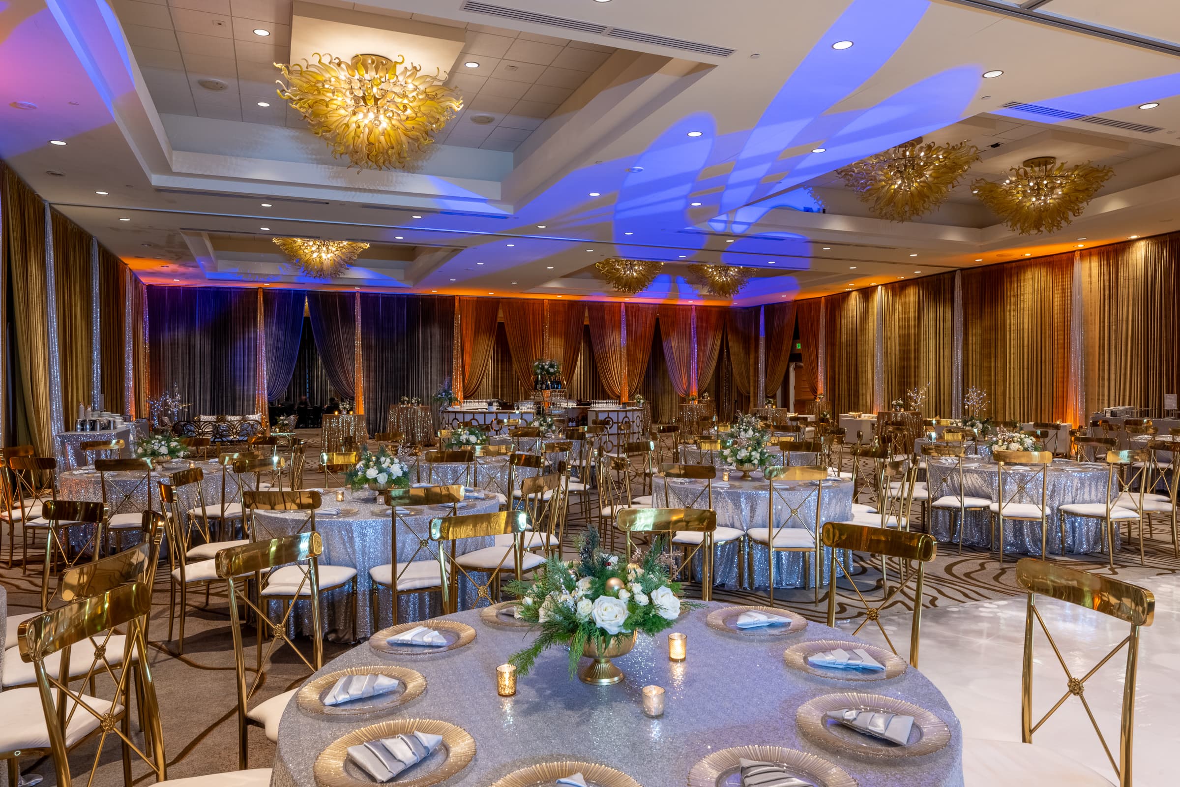 Banquet room set with gold chiavari chairs and white floral centrepieces