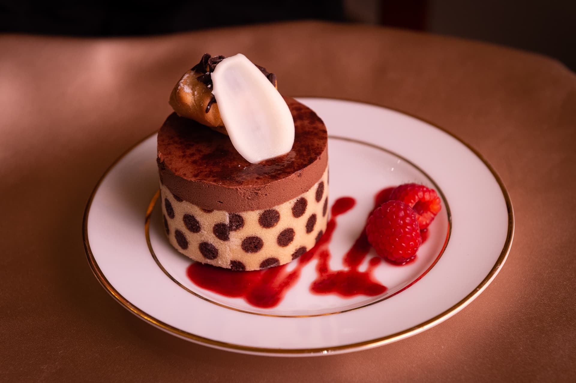 Decadent layered chocolate torte with polka dot pattern and cream topping on elegant dessert plate