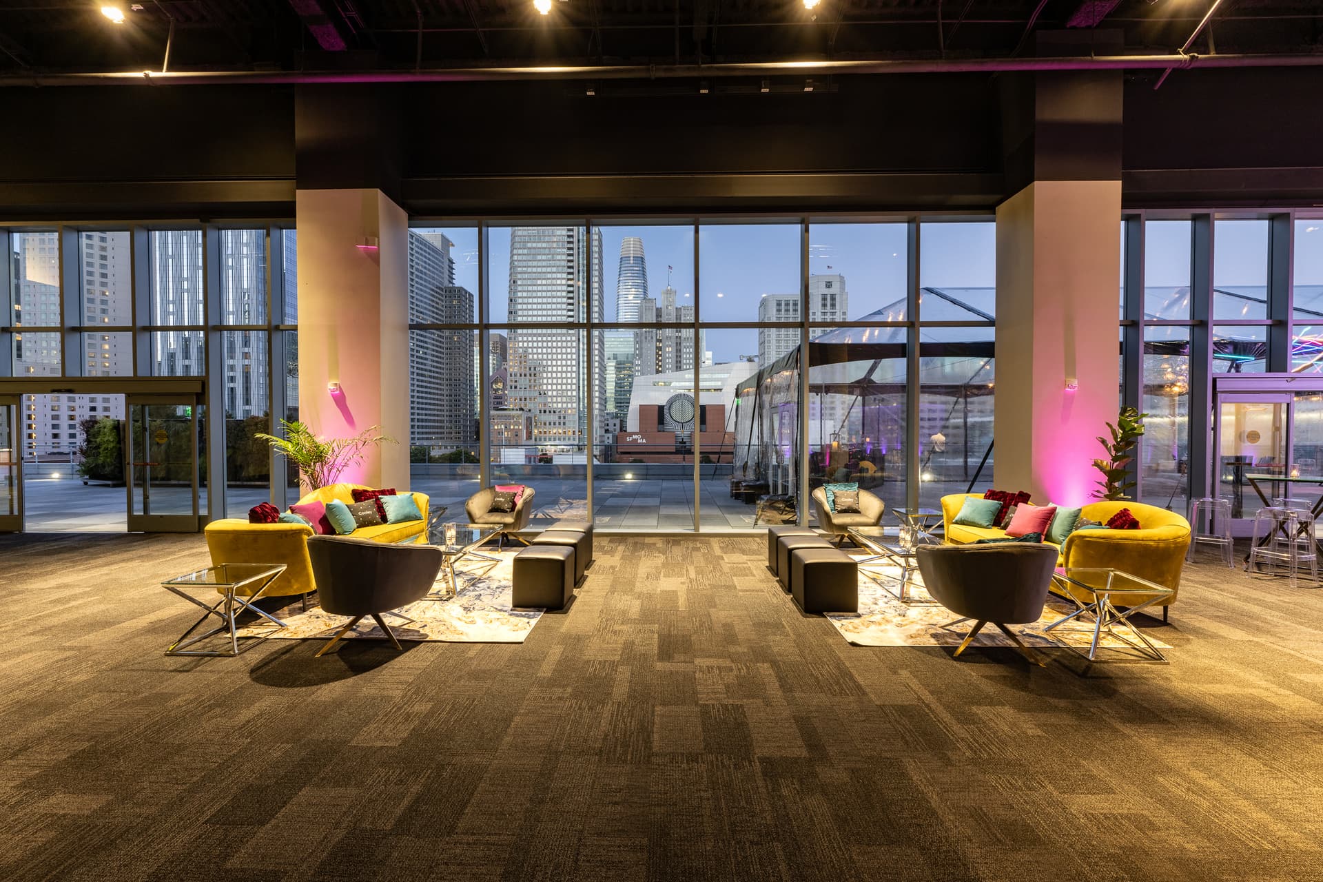 Colorful lounge chairs and sofas beside floor-to-ceiling windows at City View at Metreon