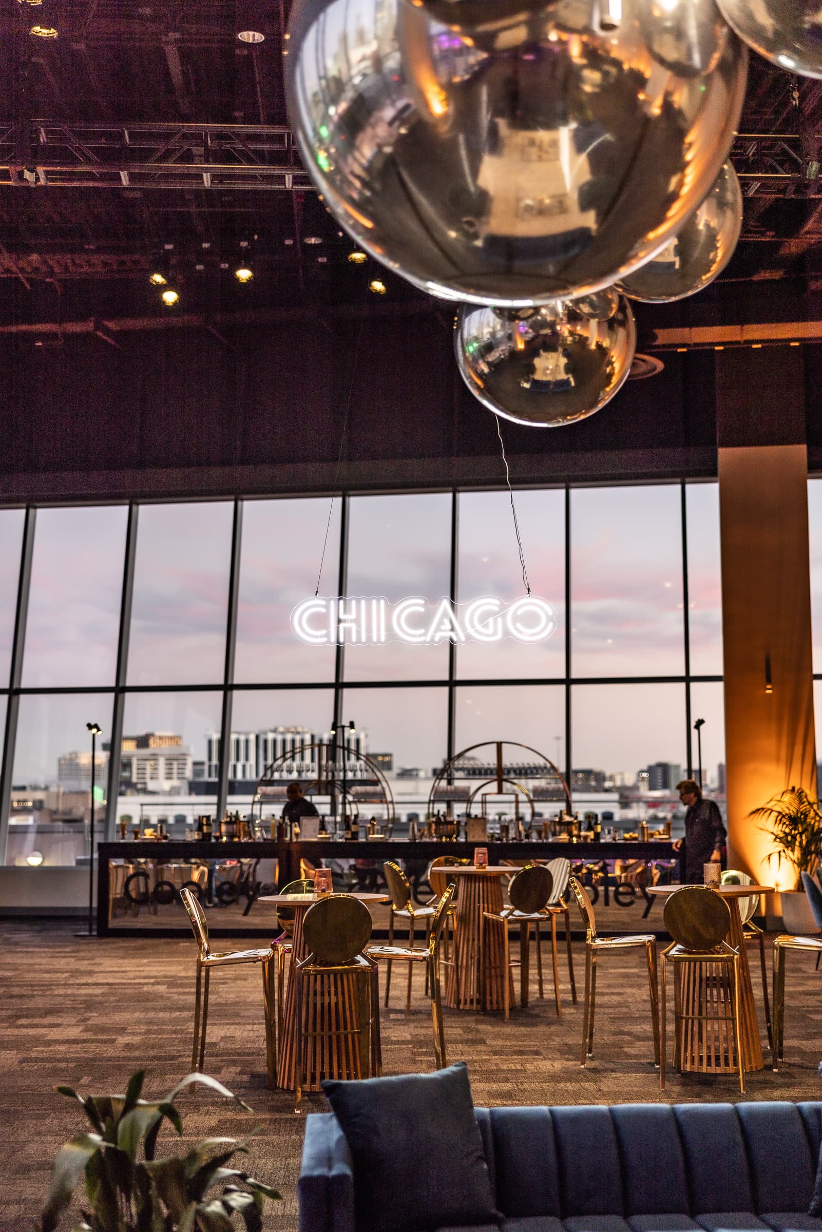 Mirrored hanging spheres above a reception lounge and bar with Chicago lettering on the windows at City View at Metreon