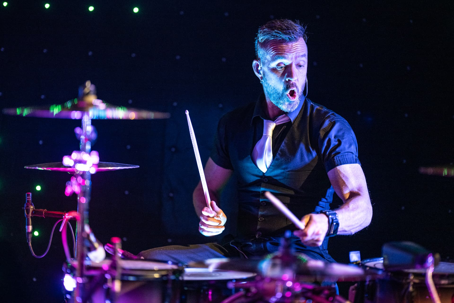 Drummer performing with dramatic purple stage lighting at corporate event