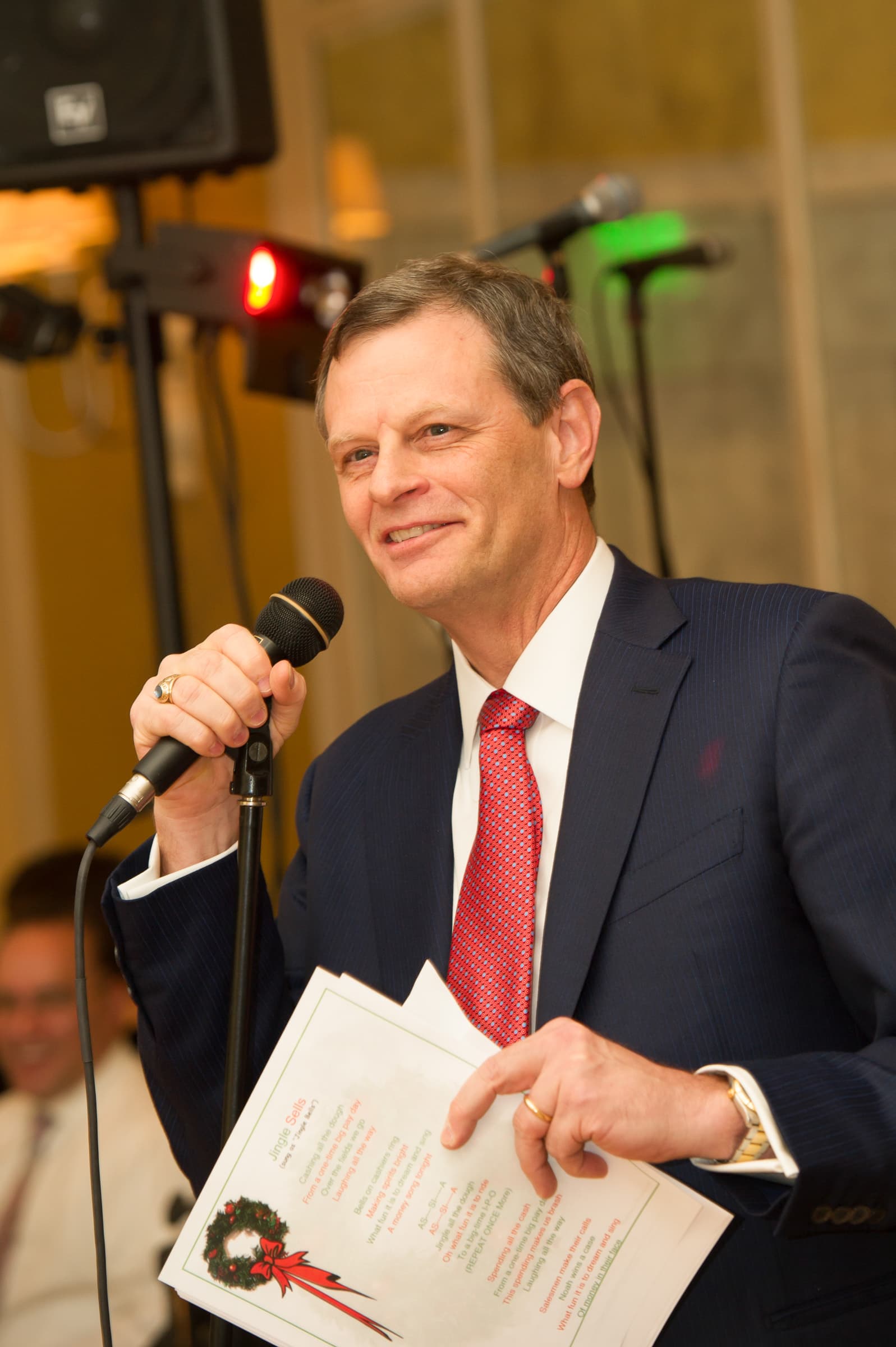 Emcee delivering remarks from handwritten notes on a handheld microphone