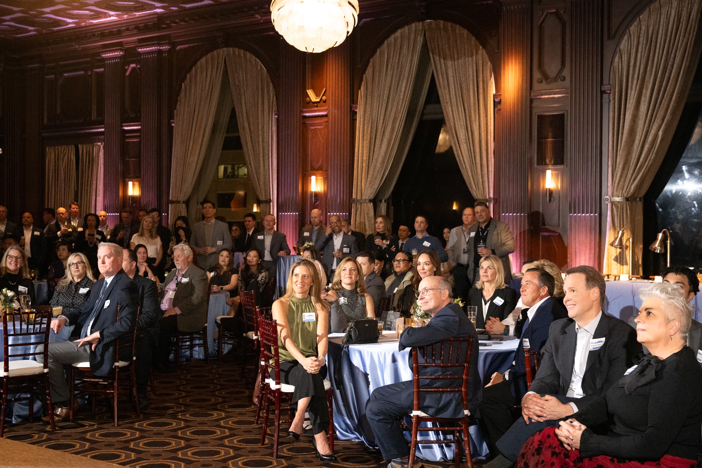 Seated guests watching the programme from banquet rounds in a wood-panelled ballroom