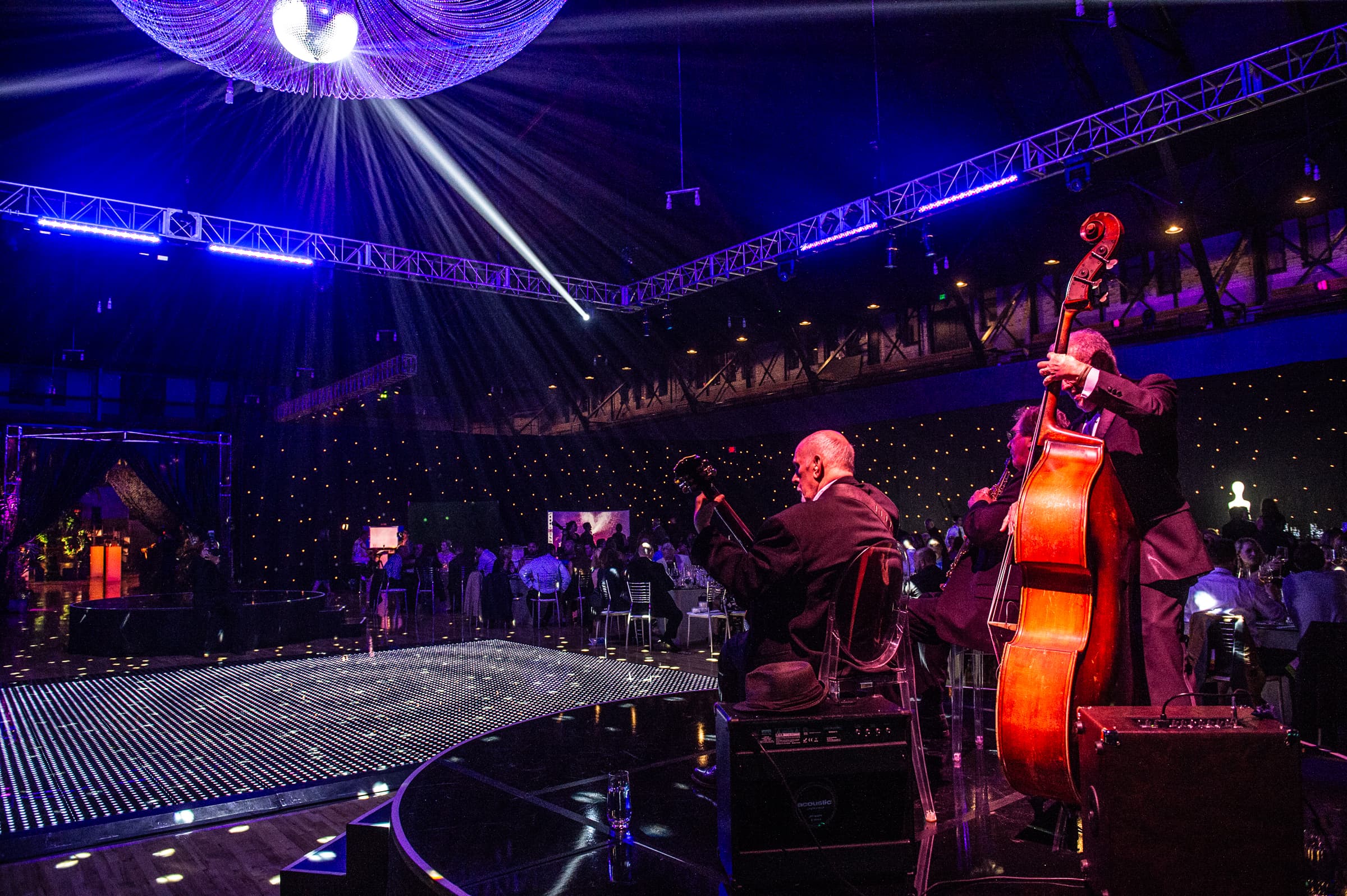 Jazz trio performing on a round stage beneath a mirror ball