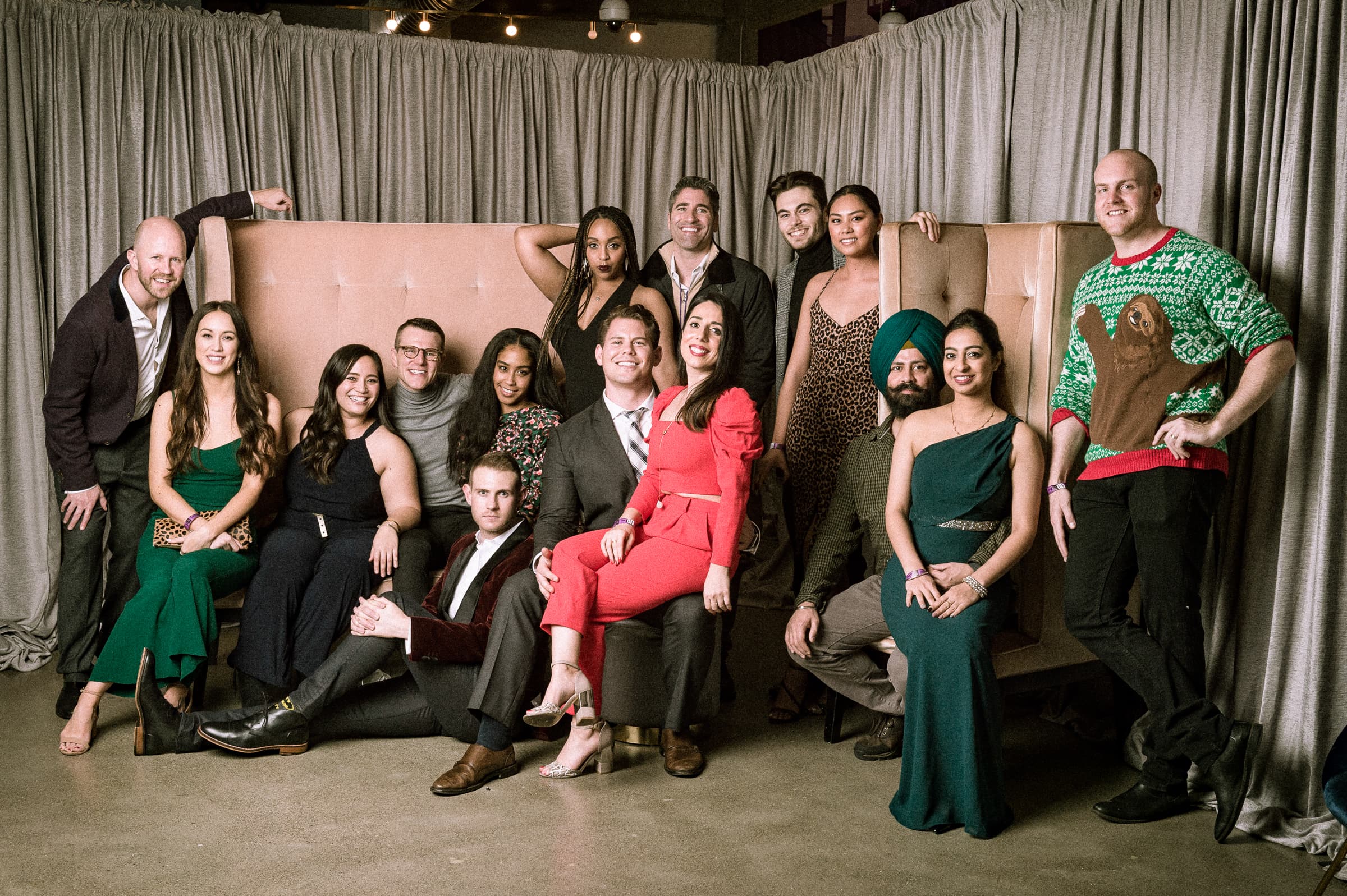 Formal group portrait of sixteen employees posed together on stage for holiday event