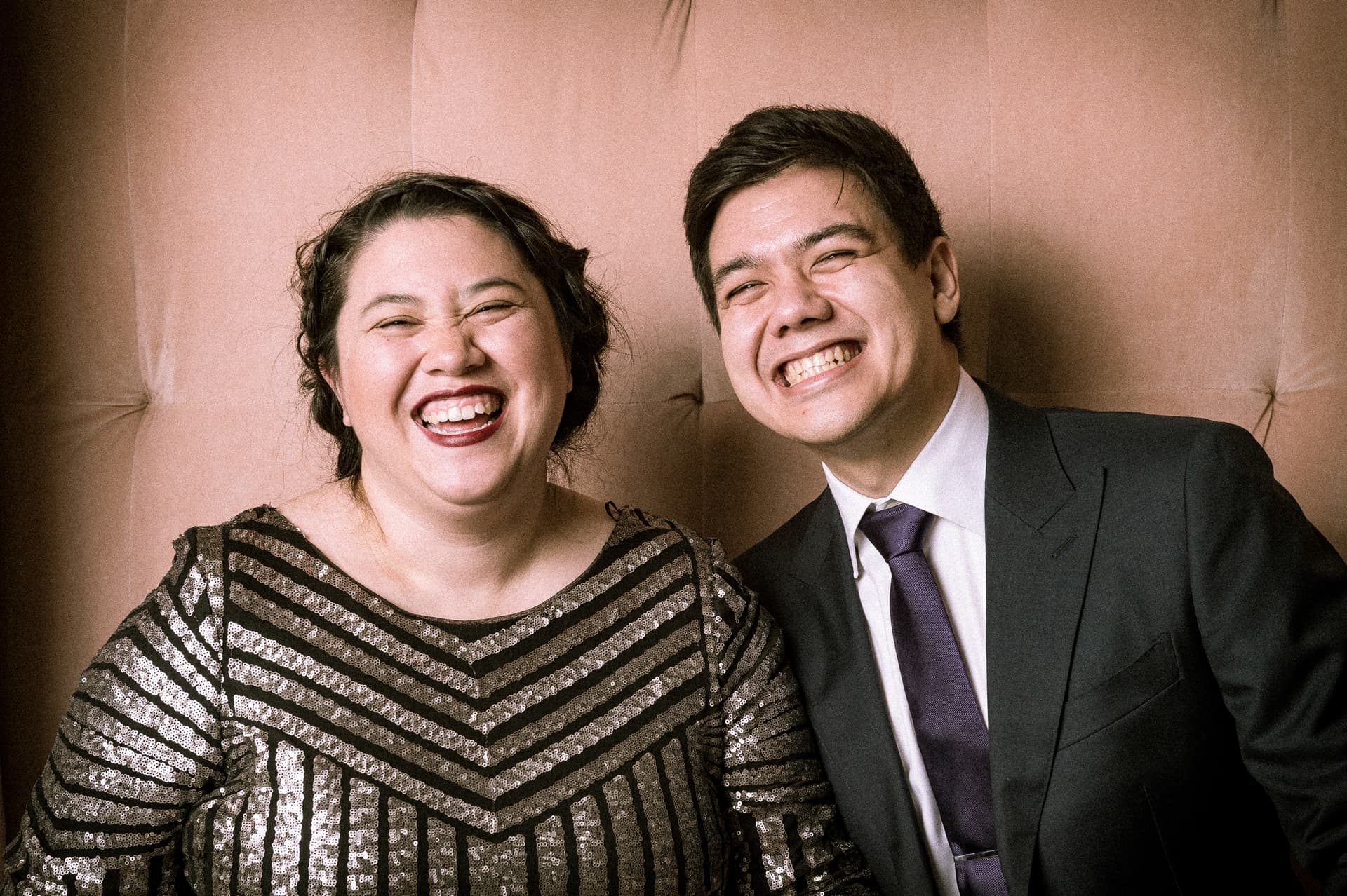 Two guests caught mid-laugh in a lit portrait vignette