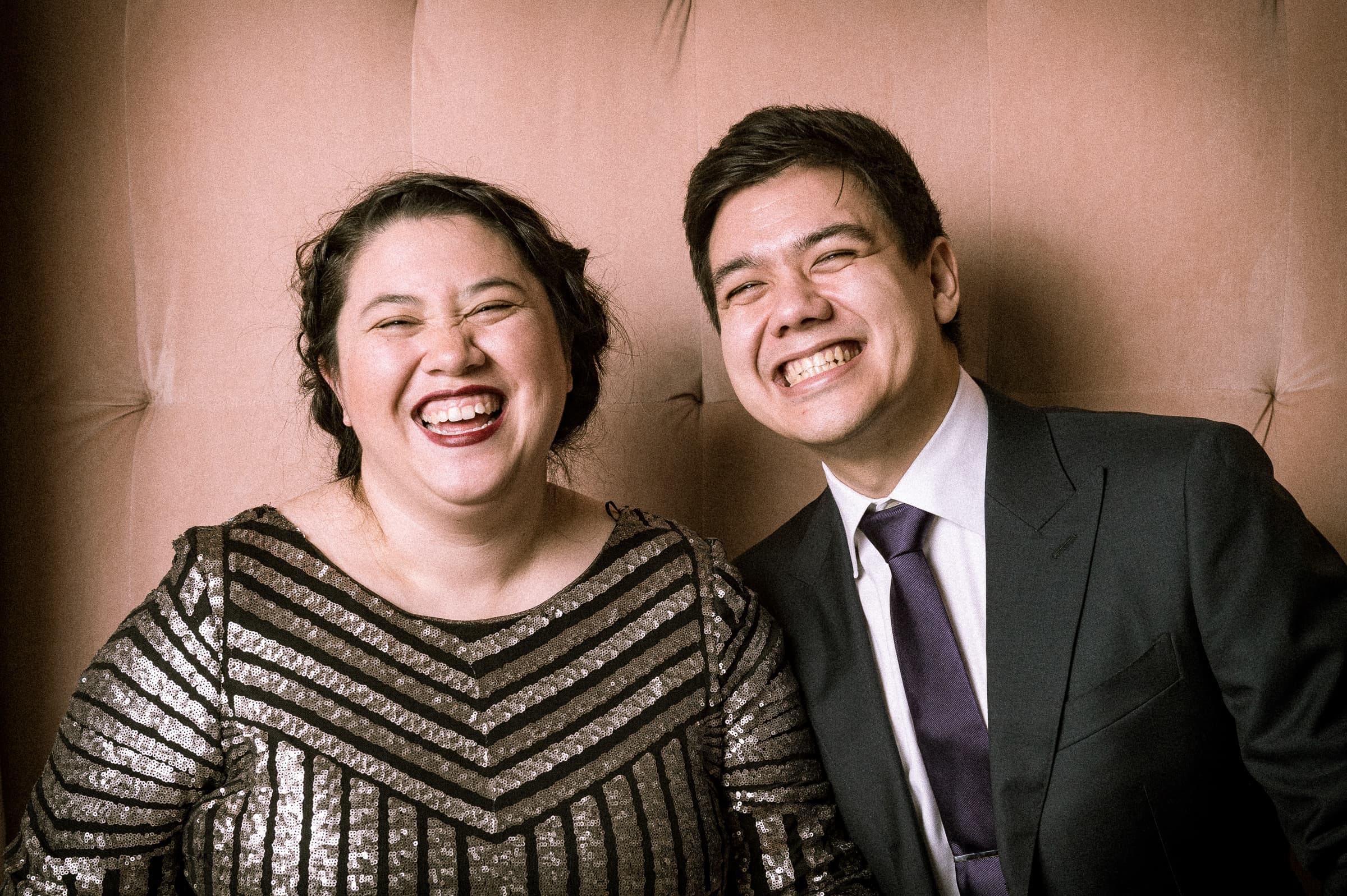 Two guests caught mid-laugh in a lit portrait vignette