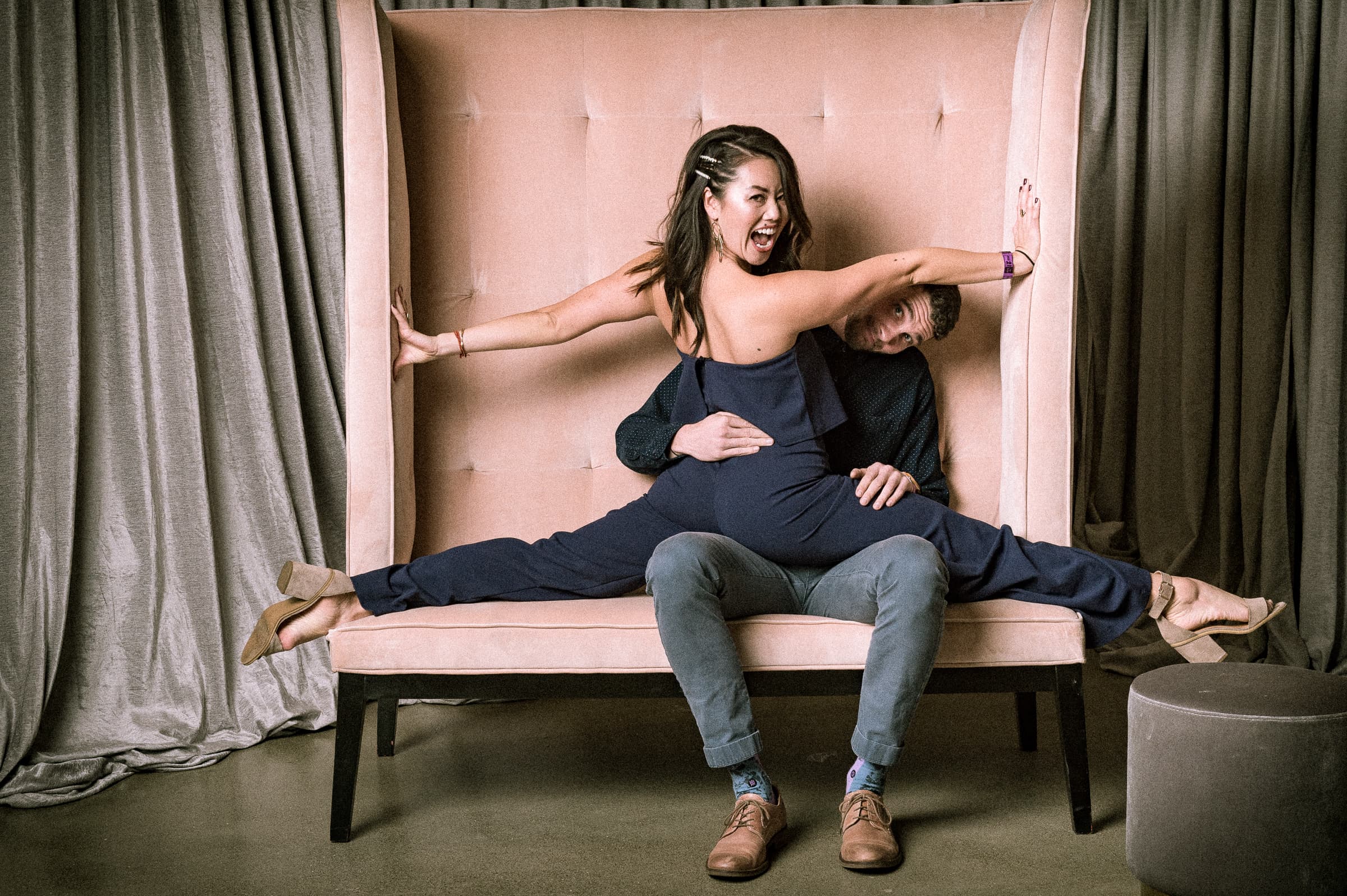 Two guests posed playfully across a velvet settee
