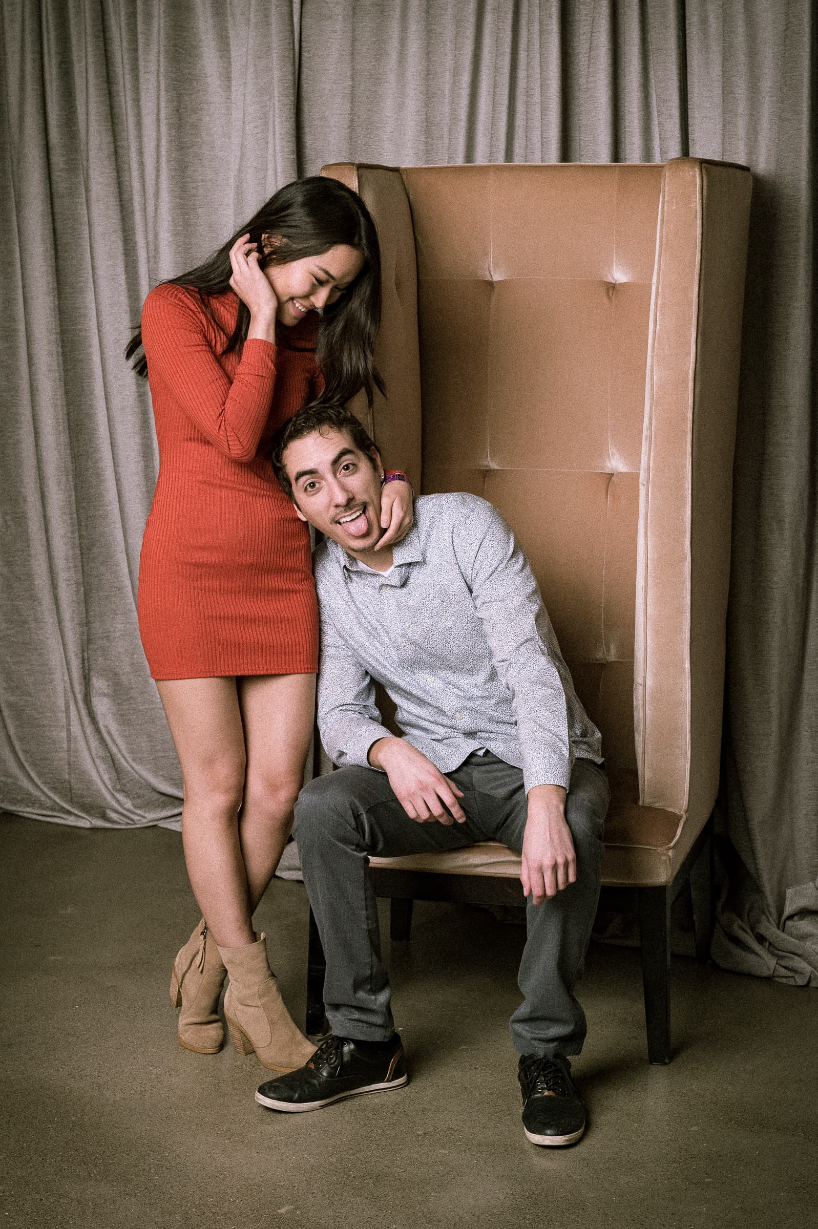 Two guests posed with a wingback chair in a portrait vignette