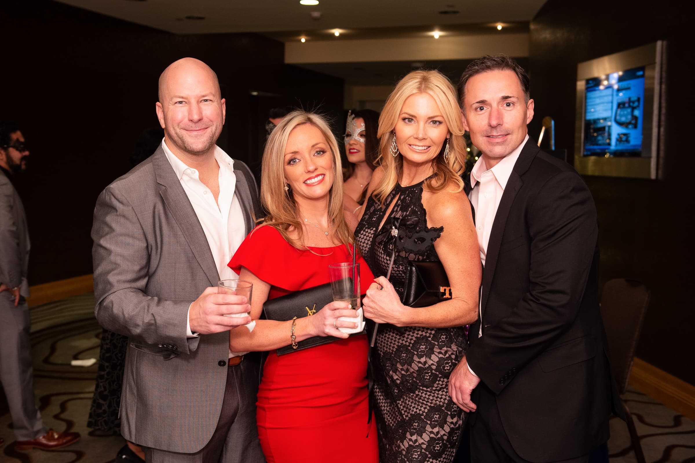 Four guests raising their drinks together at a holiday party