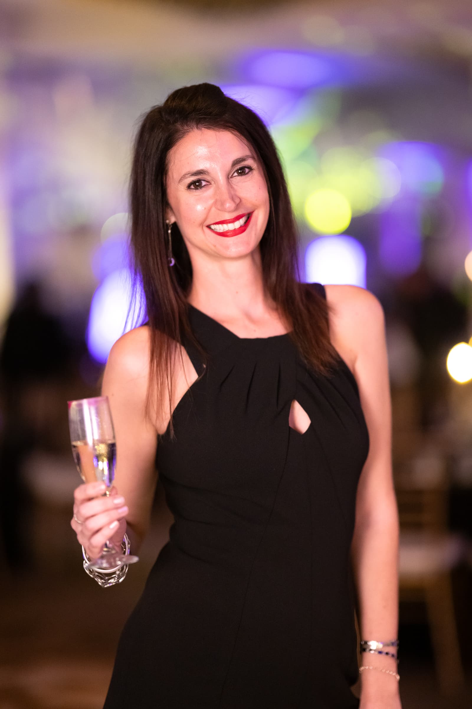 Guest with a glass of champagne photographed against party lights