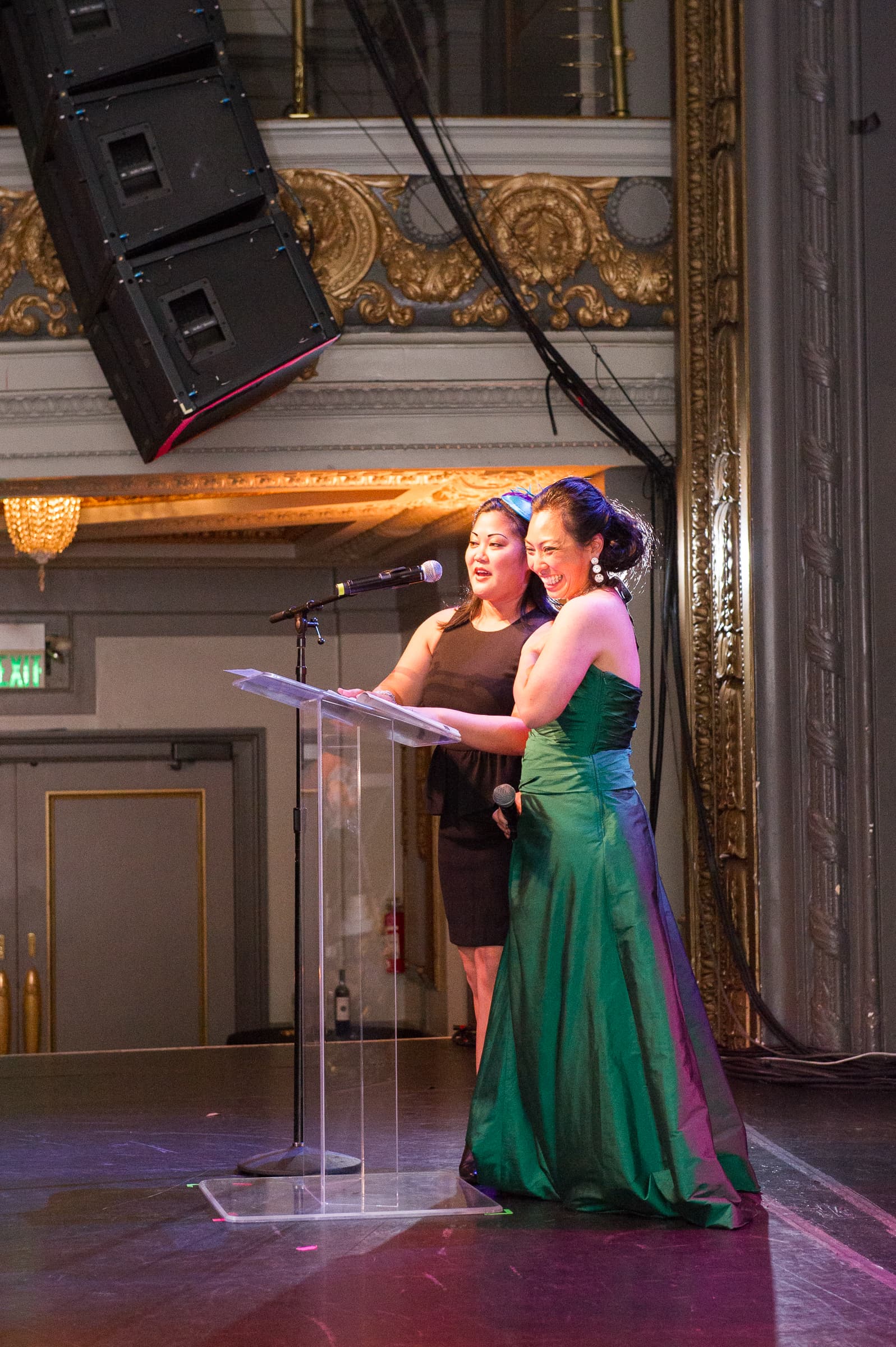 Host in an evening gown giving remarks from a lectern