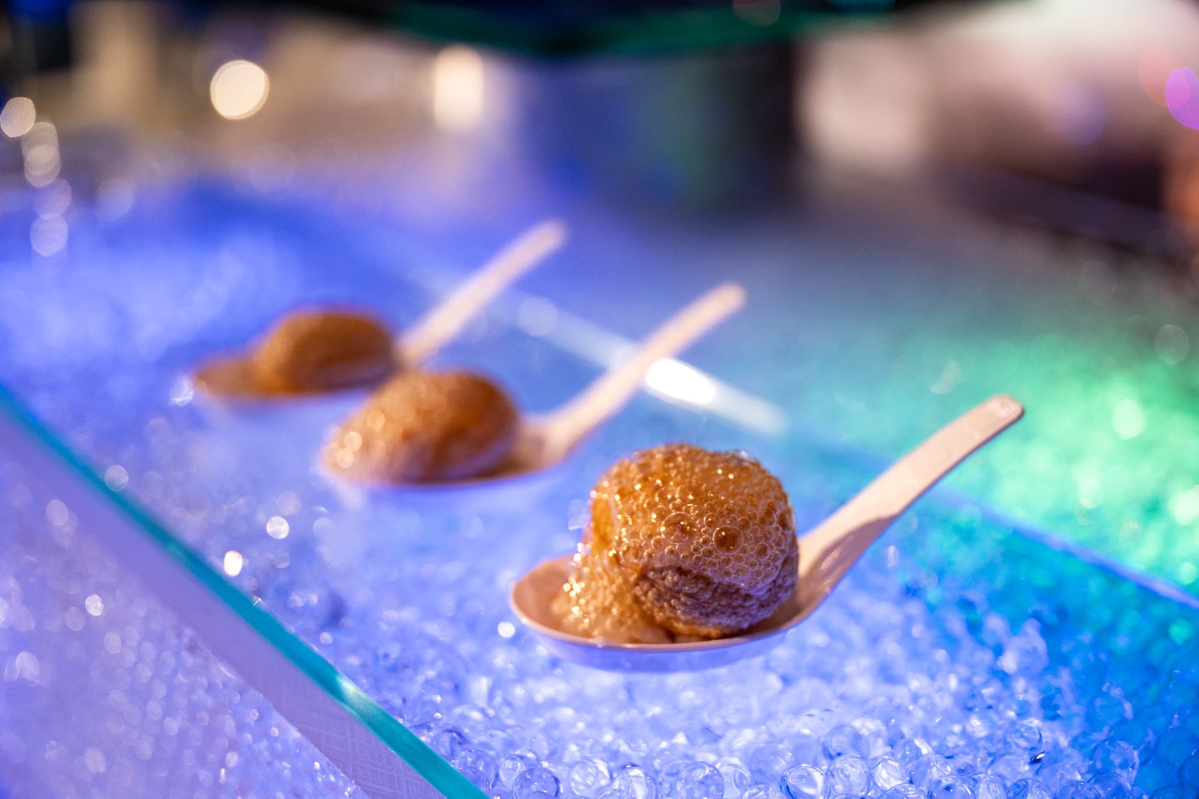 Amuse-bouche served on wooden spoons across a lit bed of crushed ice