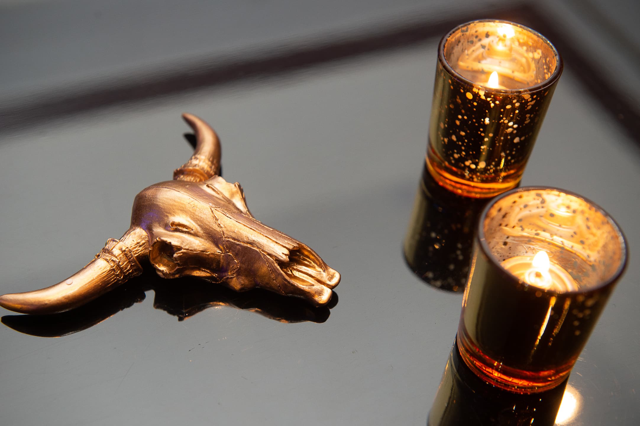 Brass animal sculpture beside mercury-glass votive candles on a table