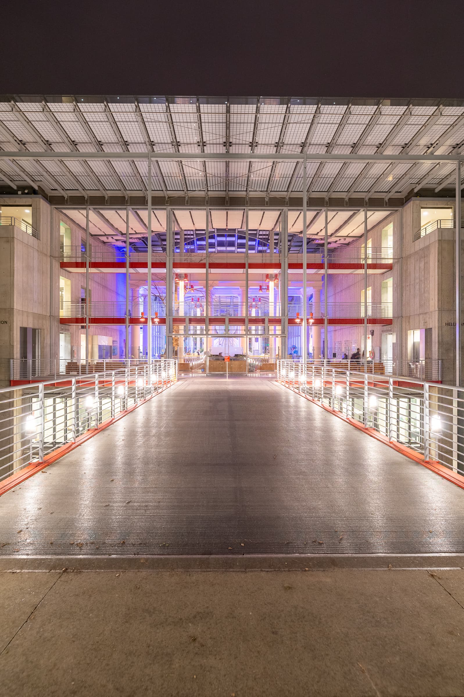 Symmetrical view along the illuminated entrance bridge to the California Academy of Sciences at night