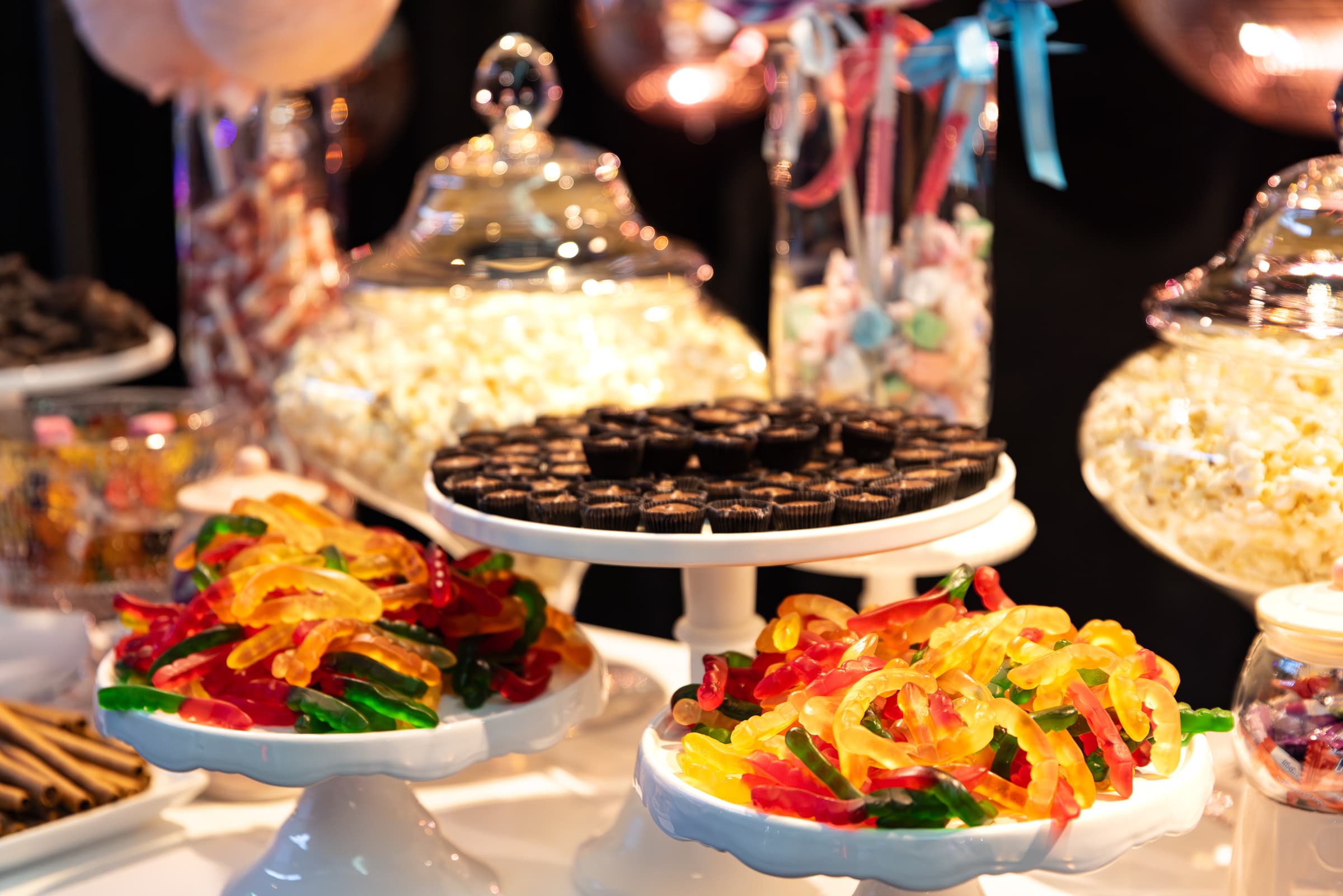 Dessert and candy display arranged across tiered stands and cloches
