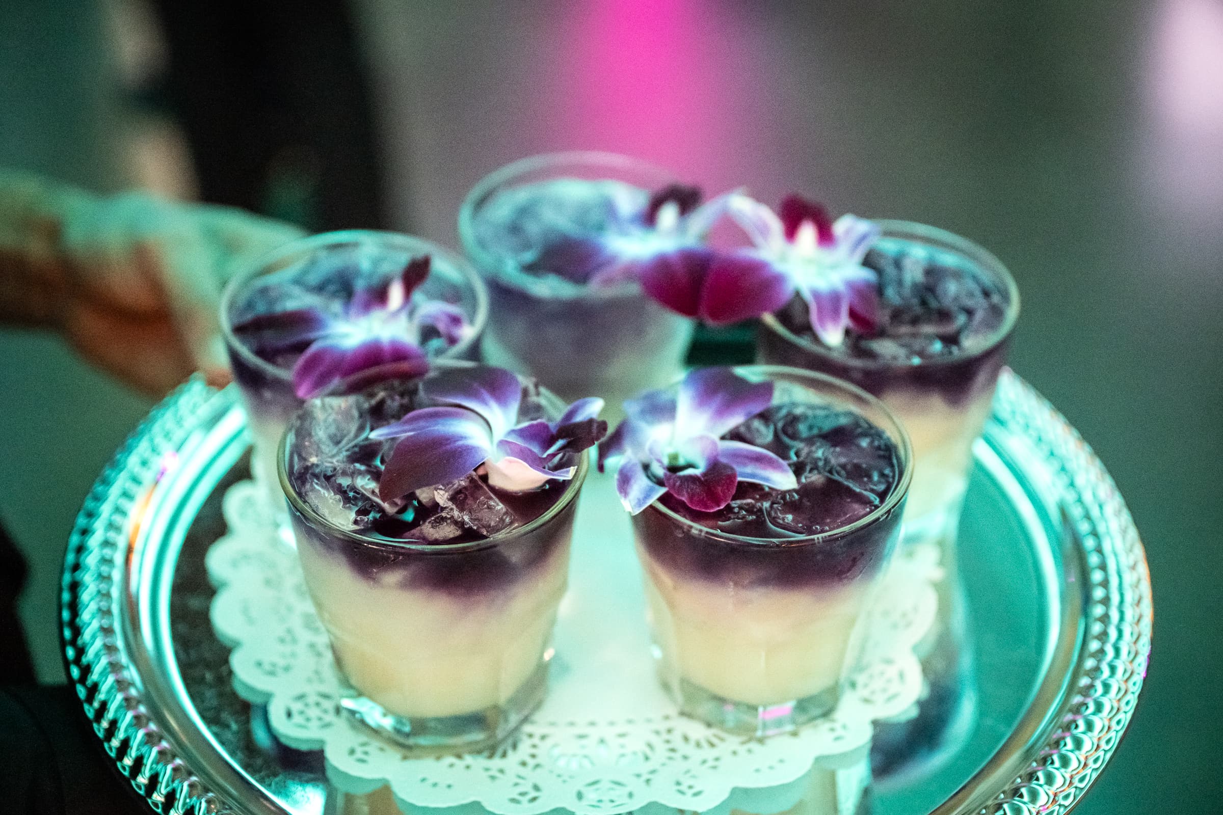 Dessert verrines topped with edible flowers on a silver tray